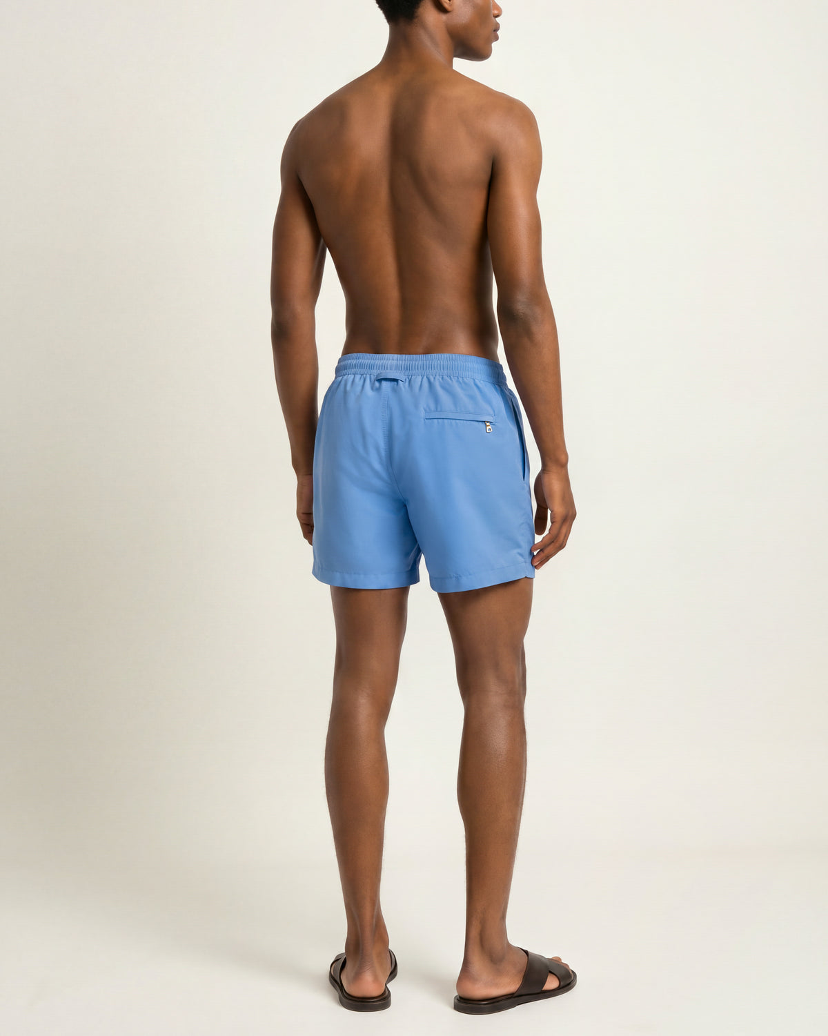 Man wearing bright blue swim shorts on a plain background