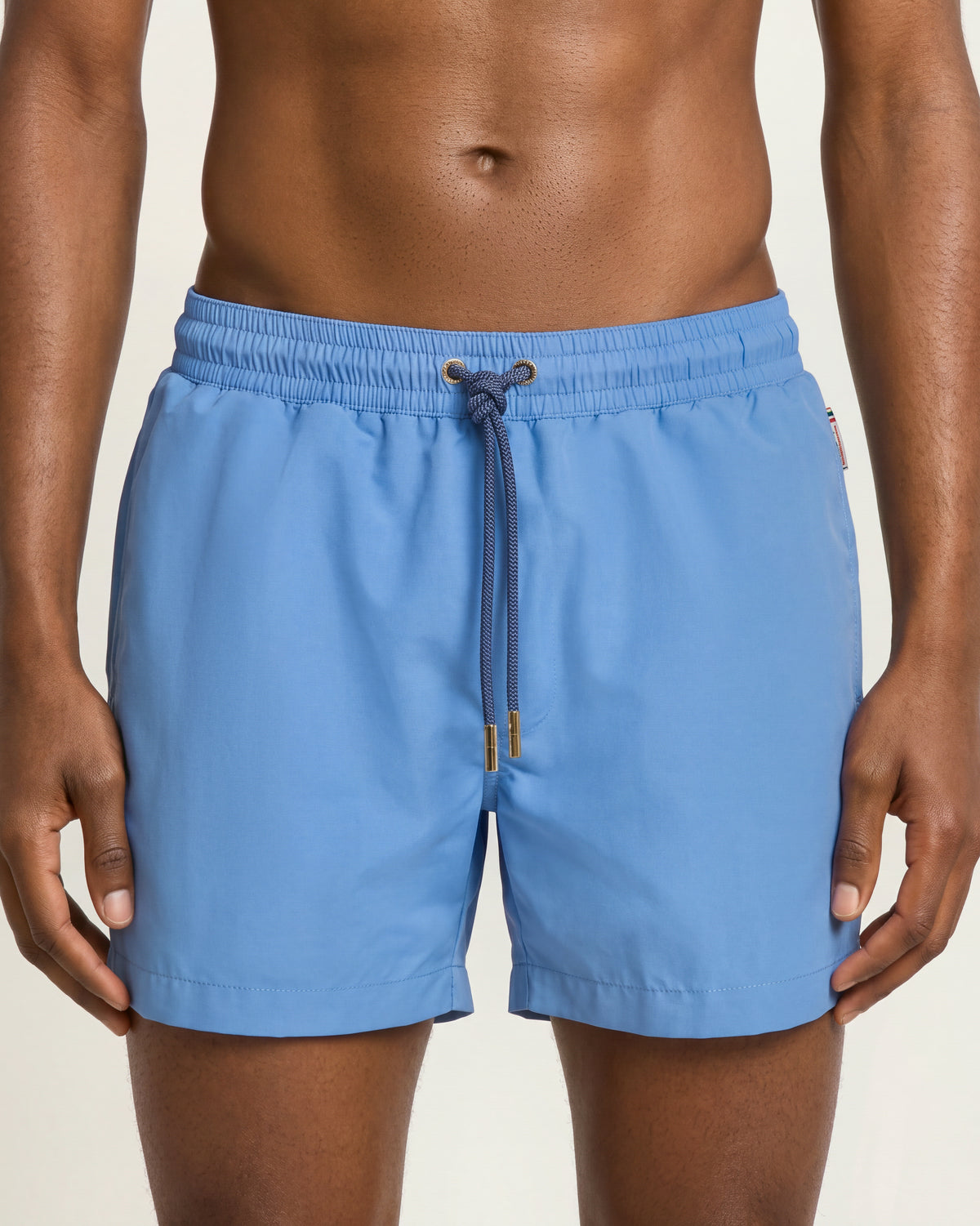 Man wearing bright blue swim shorts with drawcord waist on a plain background