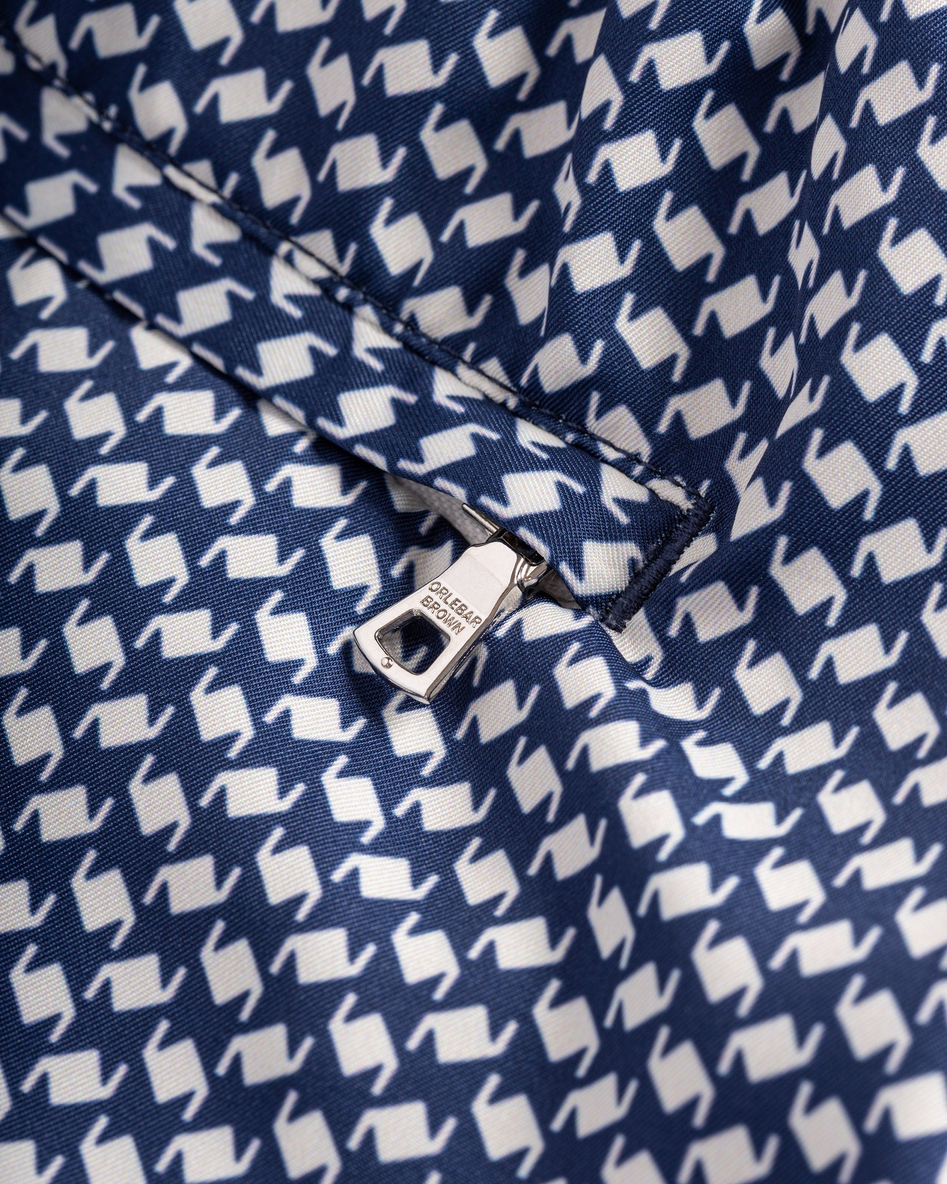 Close-up of a navy blue fabric with white geometric pattern and Colmar brand tag.