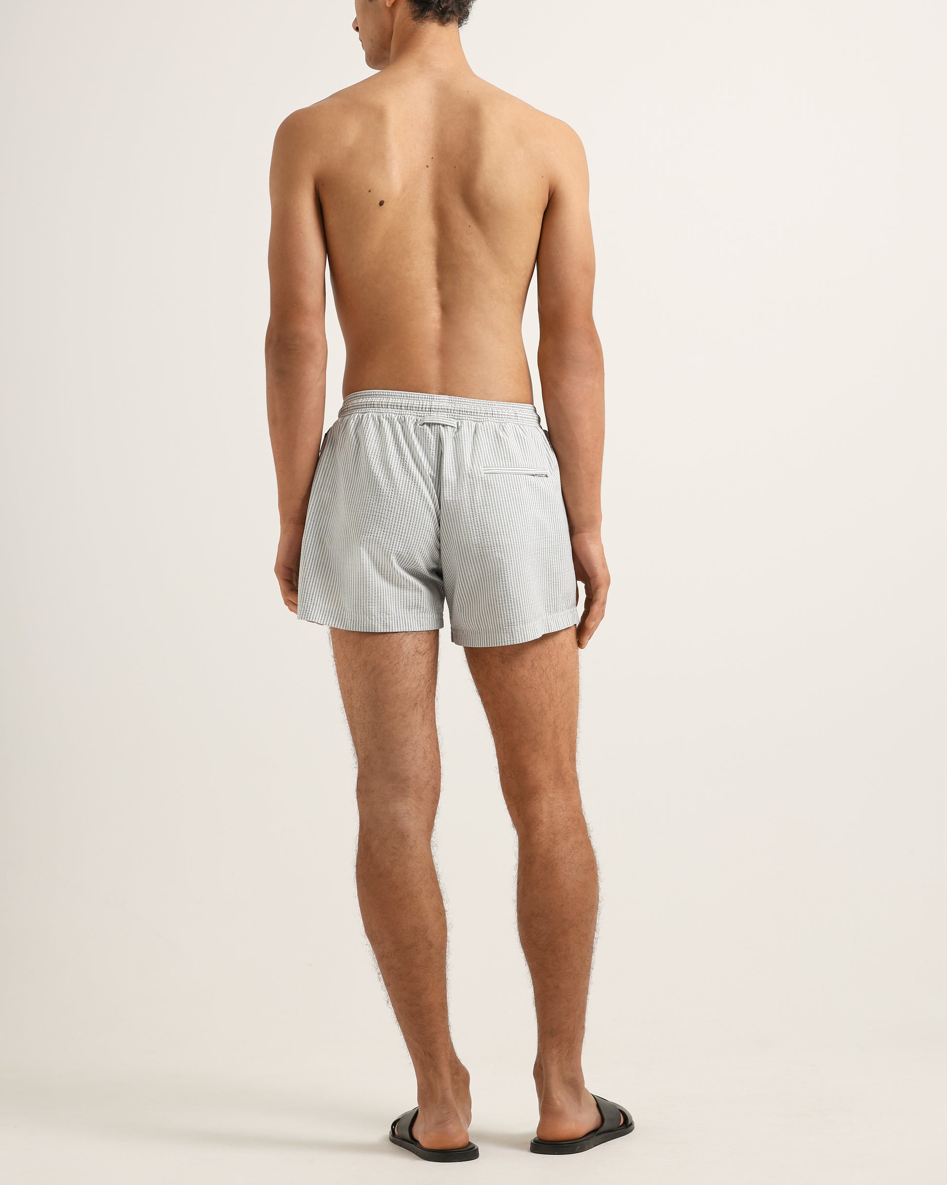 Man wearing light gray swim shorts on a plain background