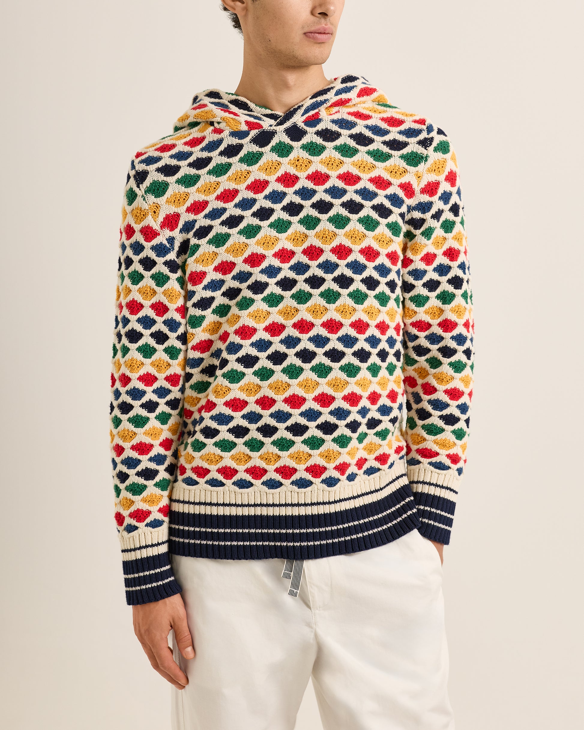 Person wearing a colorful patterned sweater against a neutral background