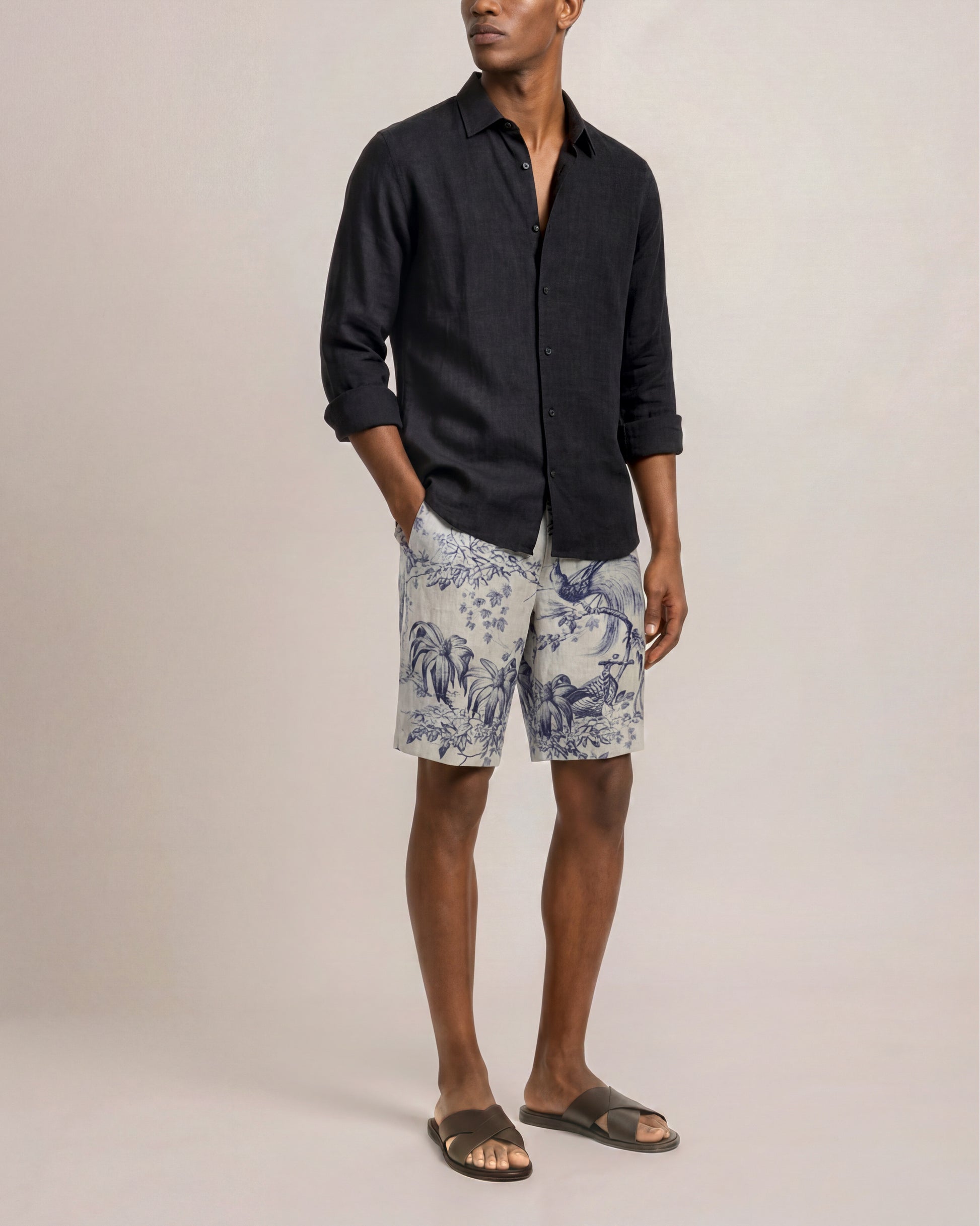 Person wearing a dark shirt and patterned shorts on a plain background