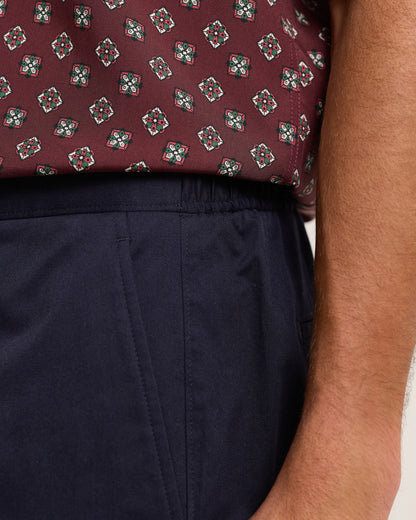 Close-up of a person wearing a patterned shirt and navy shorts.