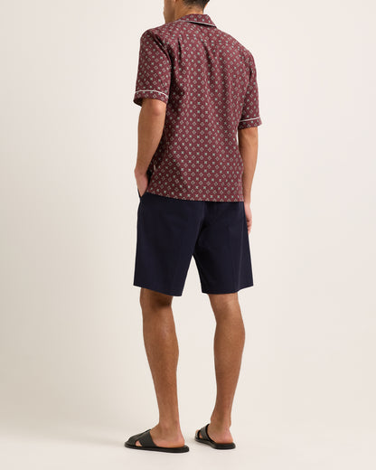 Model wearing navy shorts with maroon patterned shirt on a plain background