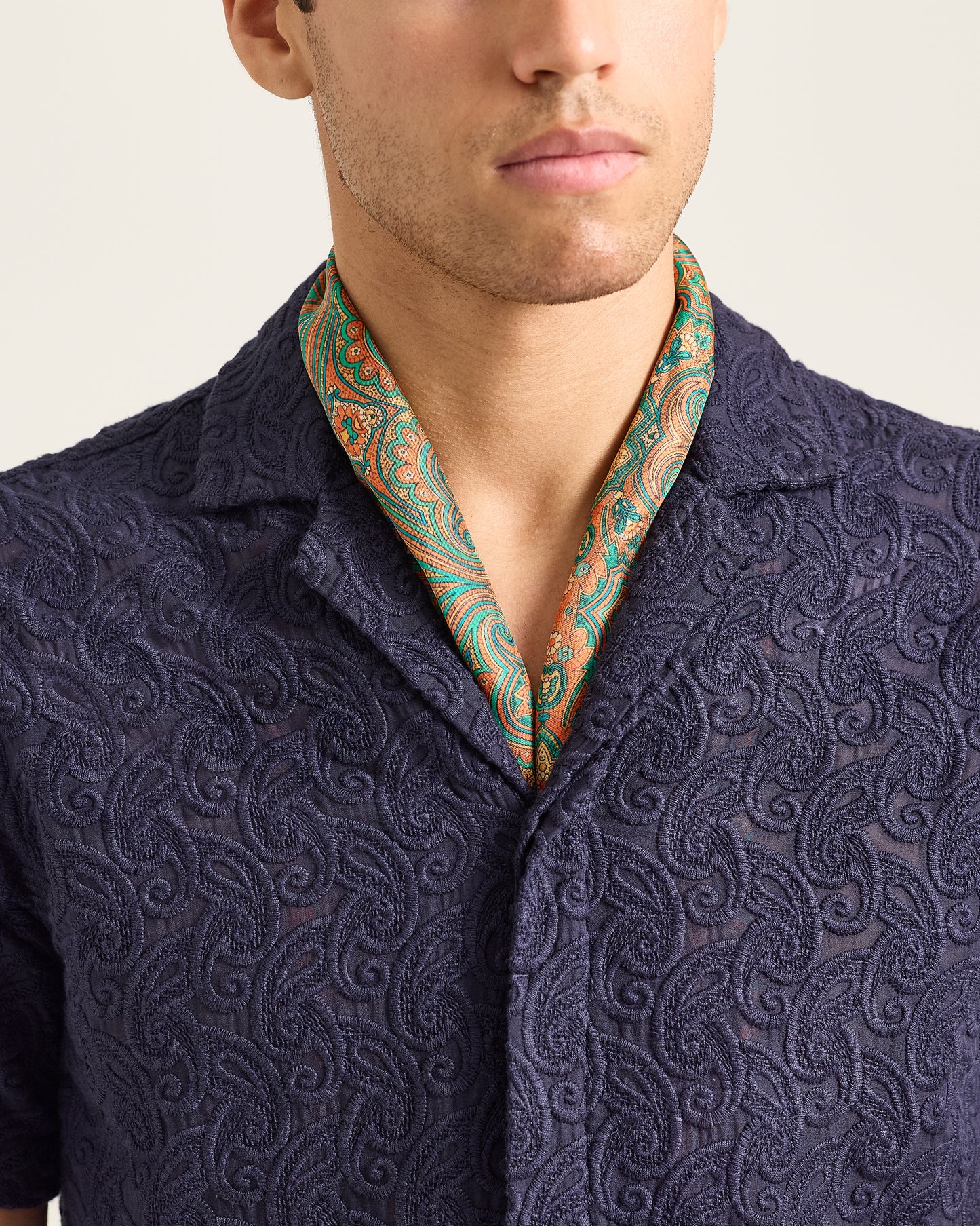 Man wearing a navy patterned shirt with a green and orange collar