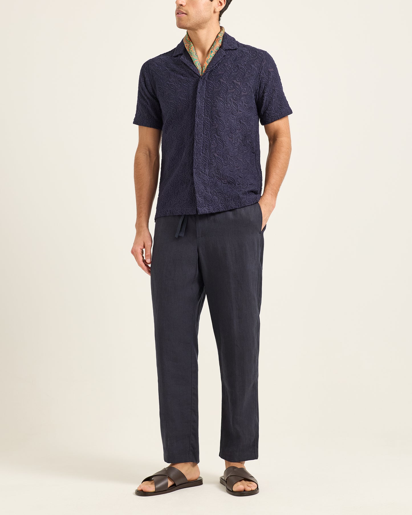 Man wearing a navy shirt and pants on a beige background