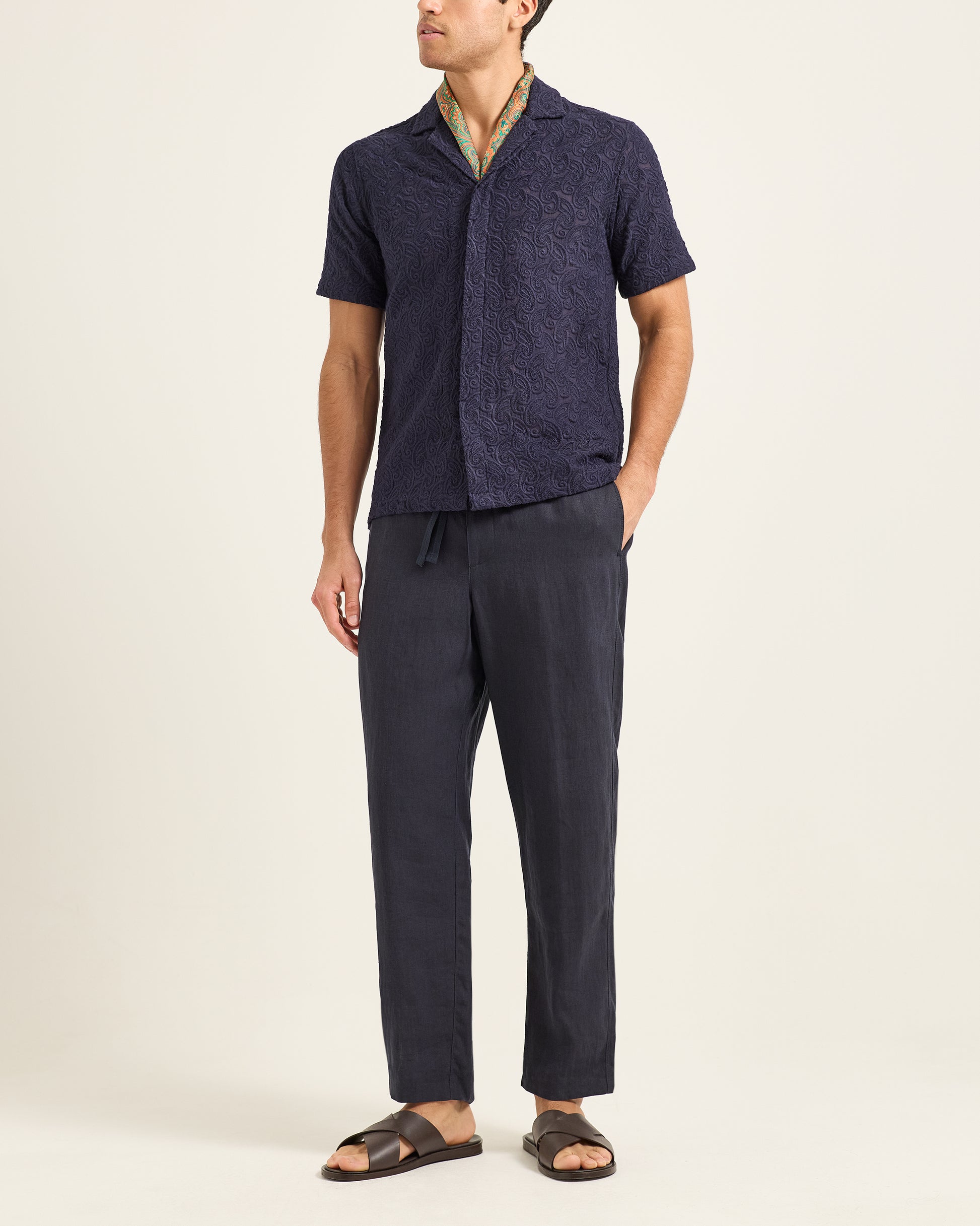 Man wearing a navy shirt and pants on a beige background