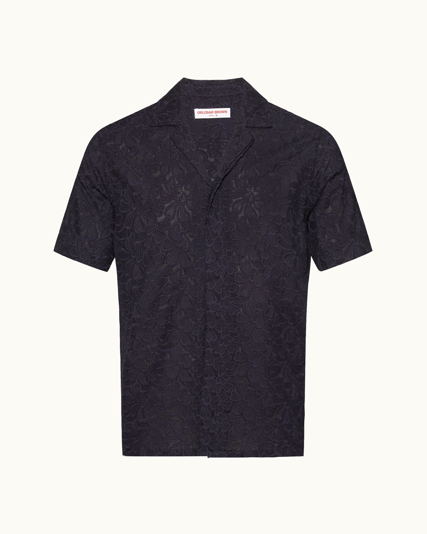 Short sleeve navy broderie anglaise shirt on a plain background