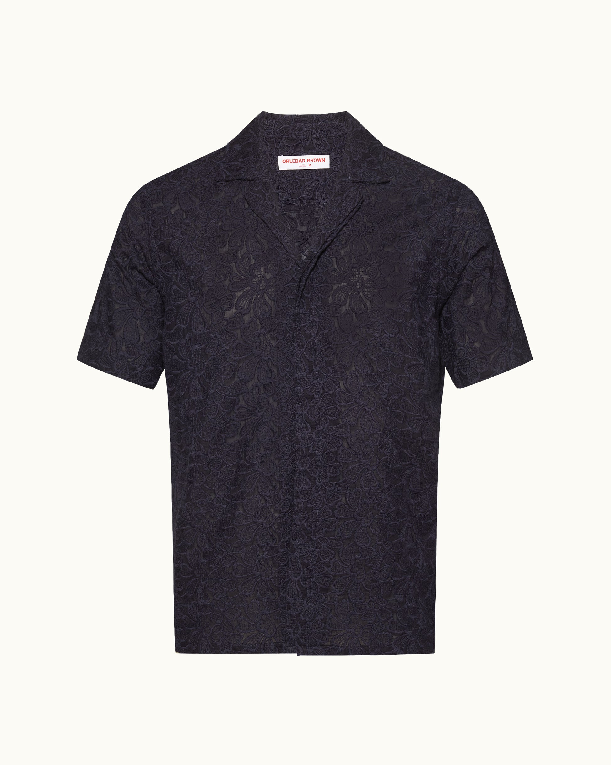 Short sleeve navy broderie anglaise shirt on a plain background
