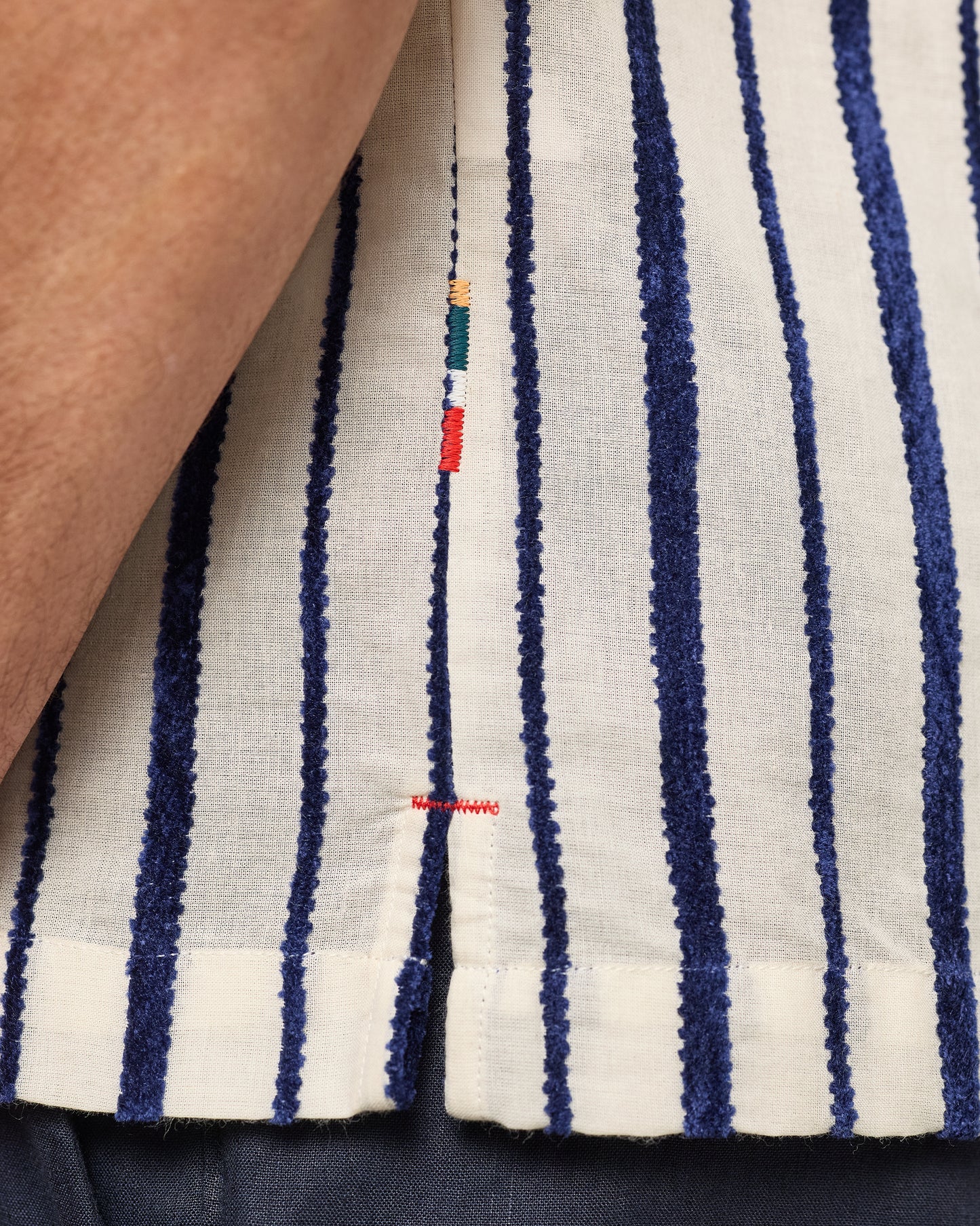 Close-up of a striped fabric with blue and white stripes, featuring a brand logo.
