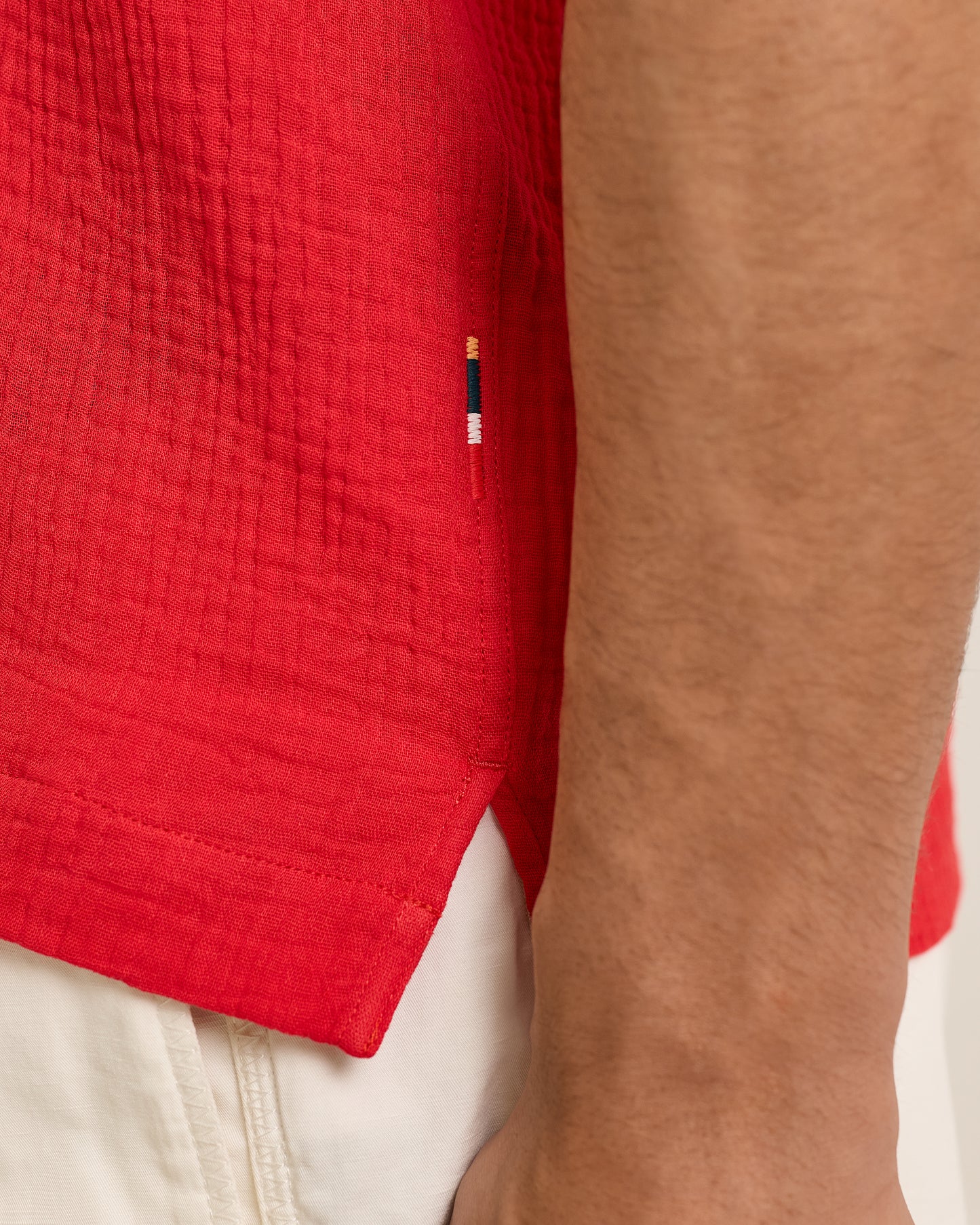 Close-up of a red garment with a brand logo on a neutral background