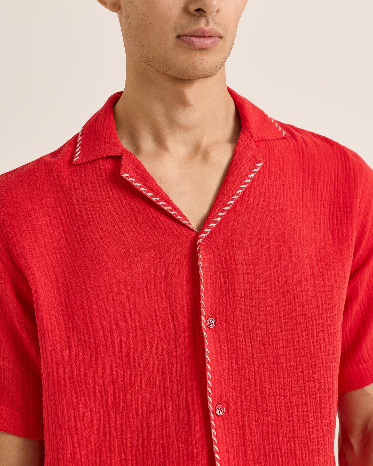 Red short-sleeve shirt with white trim on a neutral background