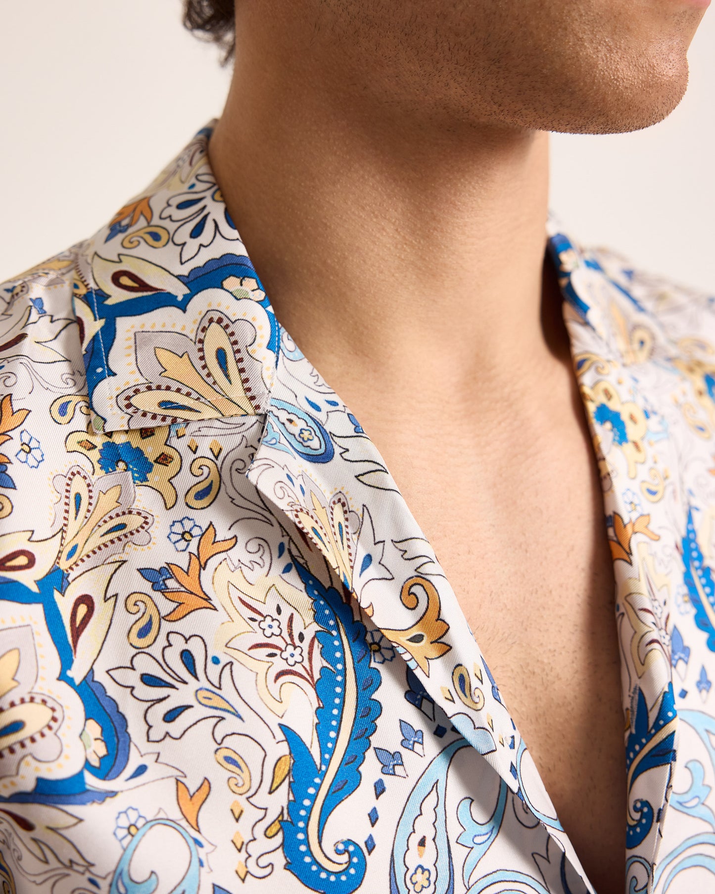 Close-up of a person wearing a patterned shirt with blue, orange, and beige colors.