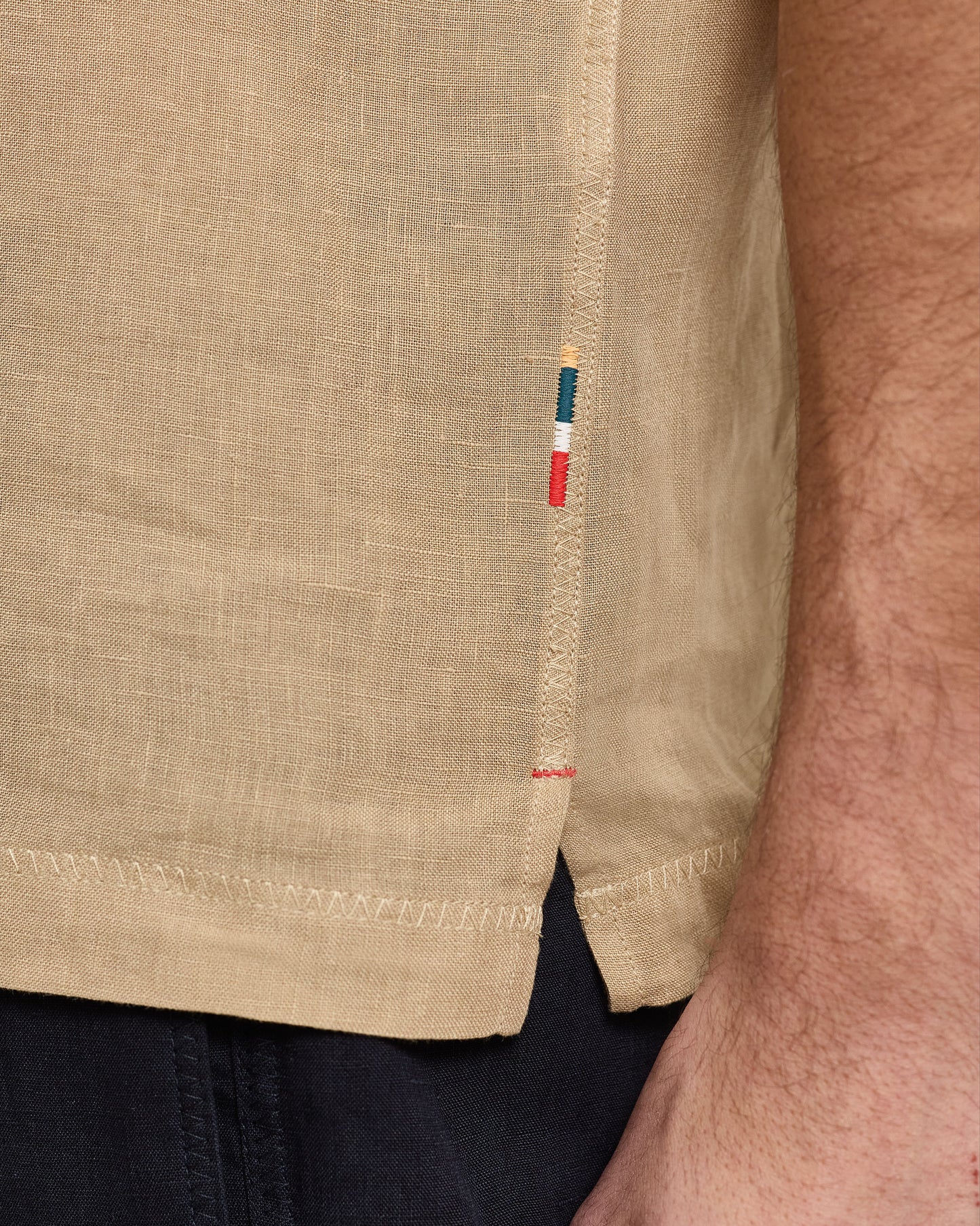 Close-up of a beige shirt with a brand label on the sleeve