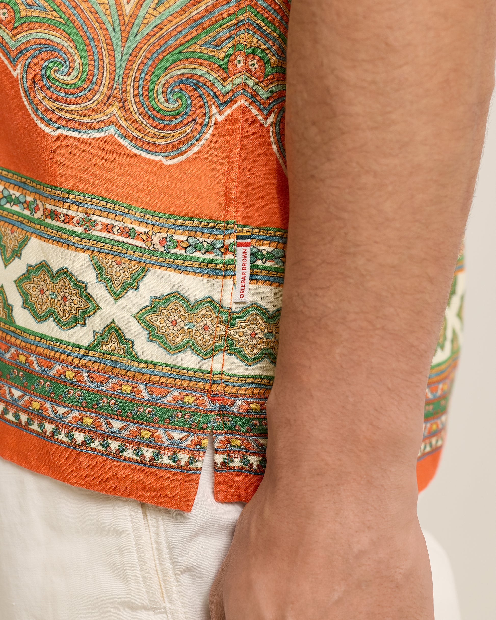 Close-up of a colorful patterned fabric with a brand label on a white background