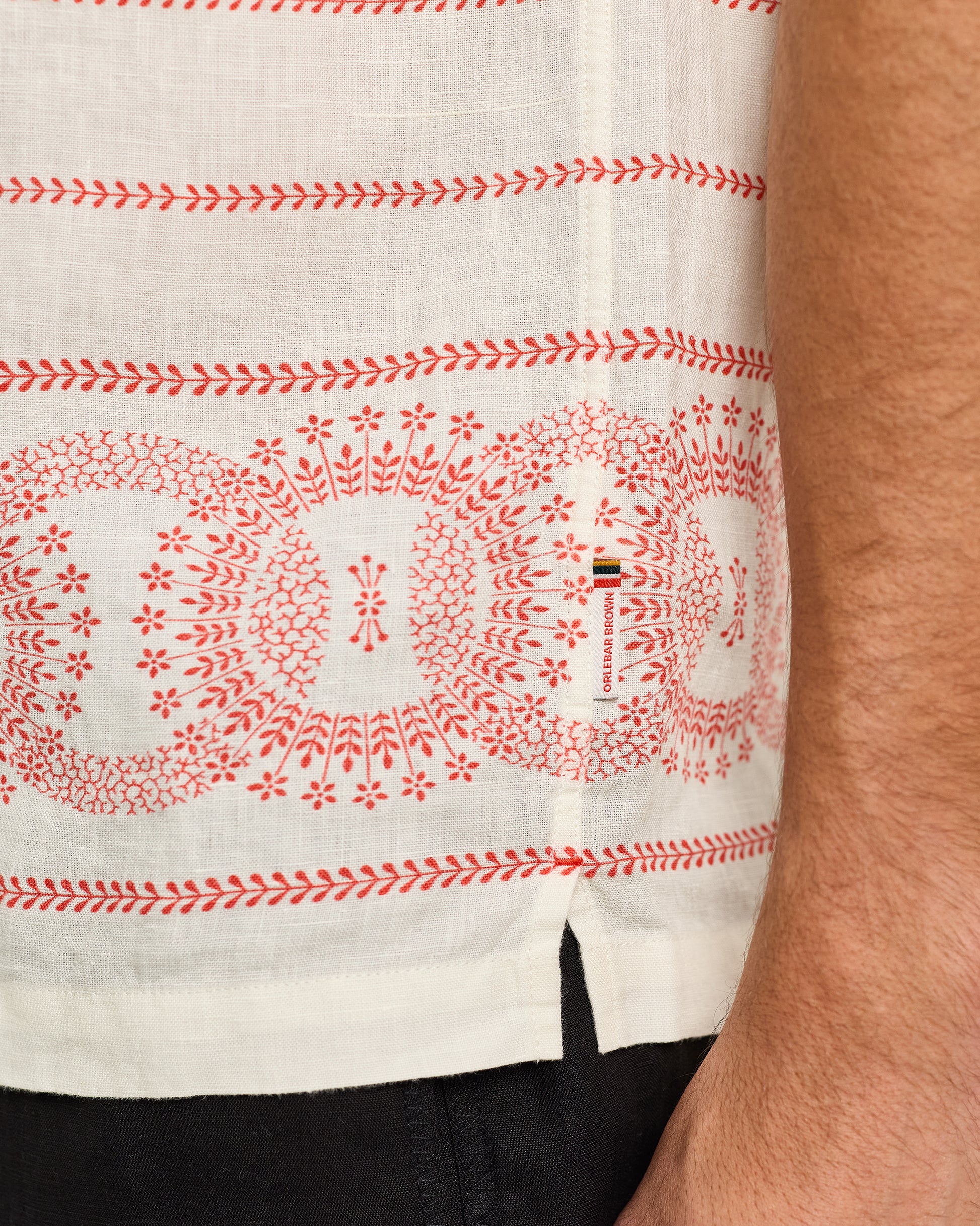 Close-up of a white shirt with red patterns and a visible brand logo.