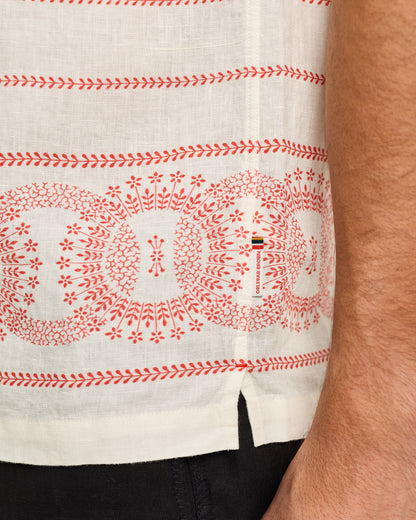 Close-up of a white shirt with red patterns and a visible brand logo.