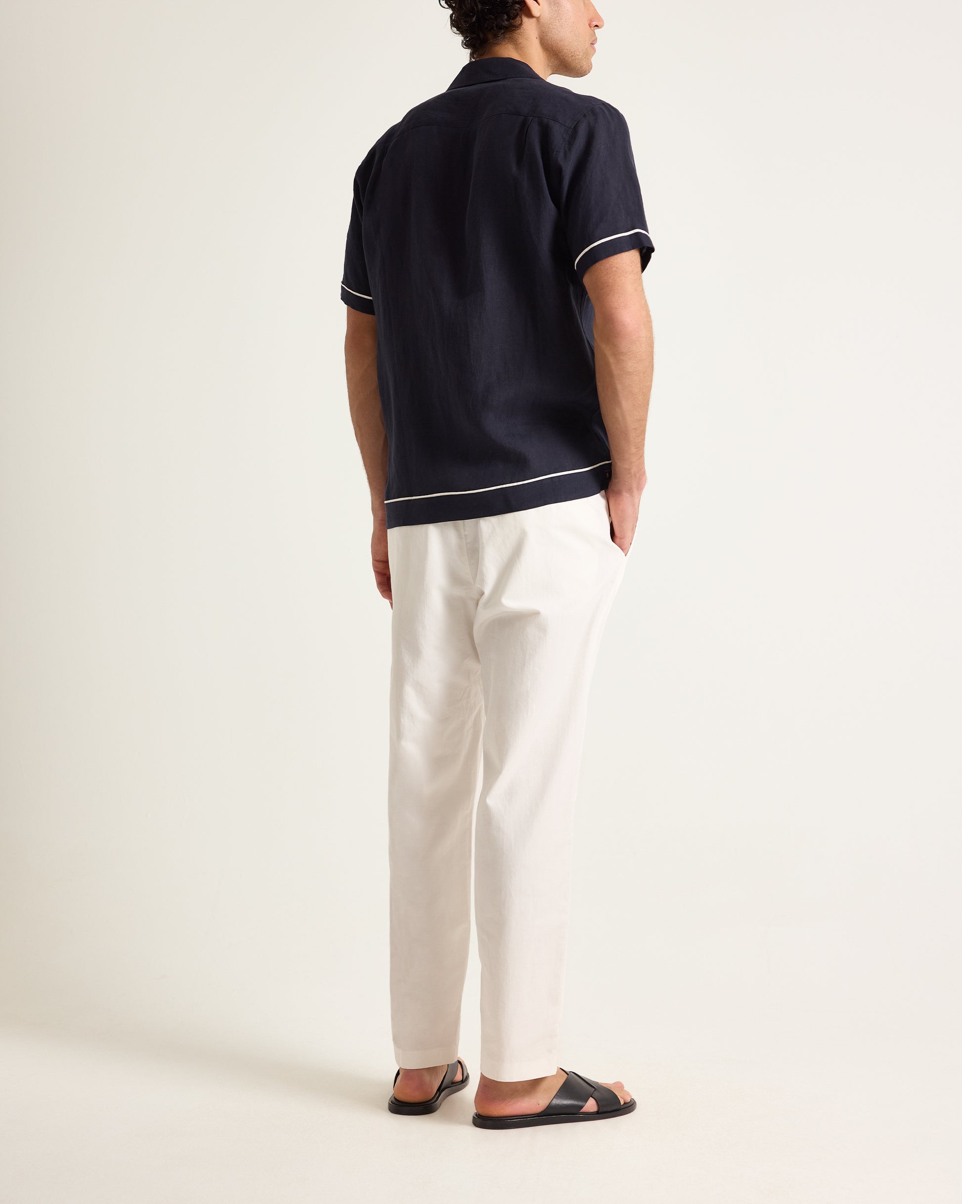 Person wearing a polo shirt with white trim and light-colored pants on a plain background