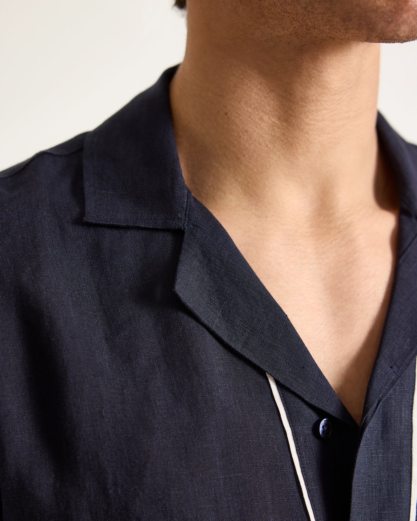 Close-up of a person wearing a dark blue shirt with a collar.