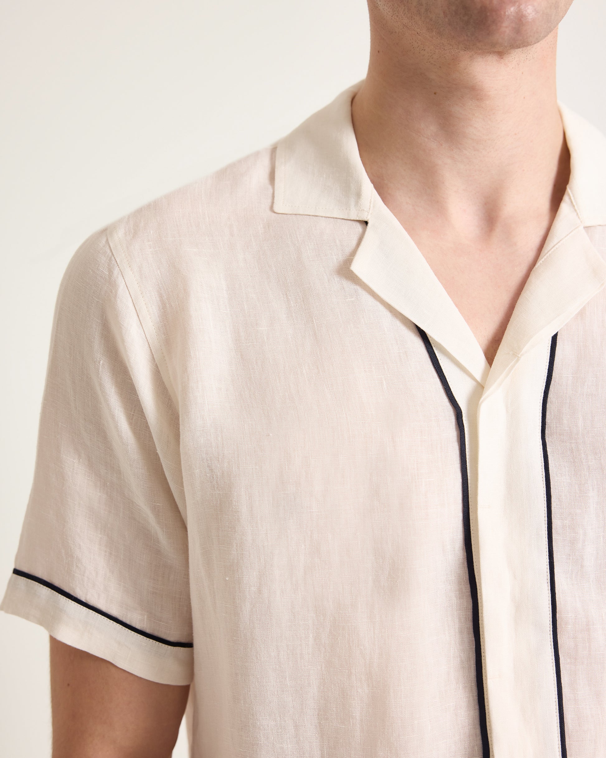 Close-up of a person wearing a white shirt with black trim on a white background