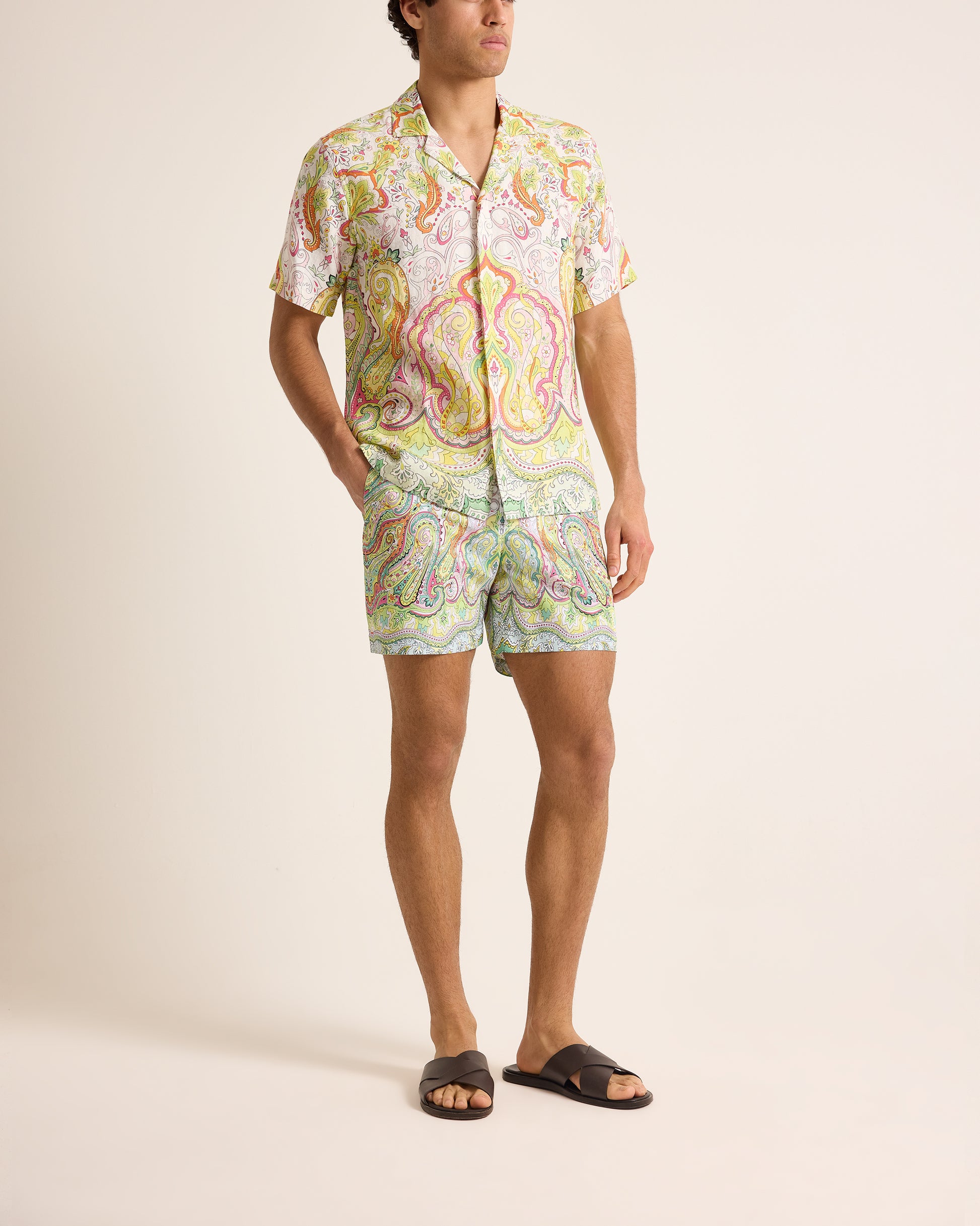 Person wearing a colorful patterned shirt and shorts on a plain background