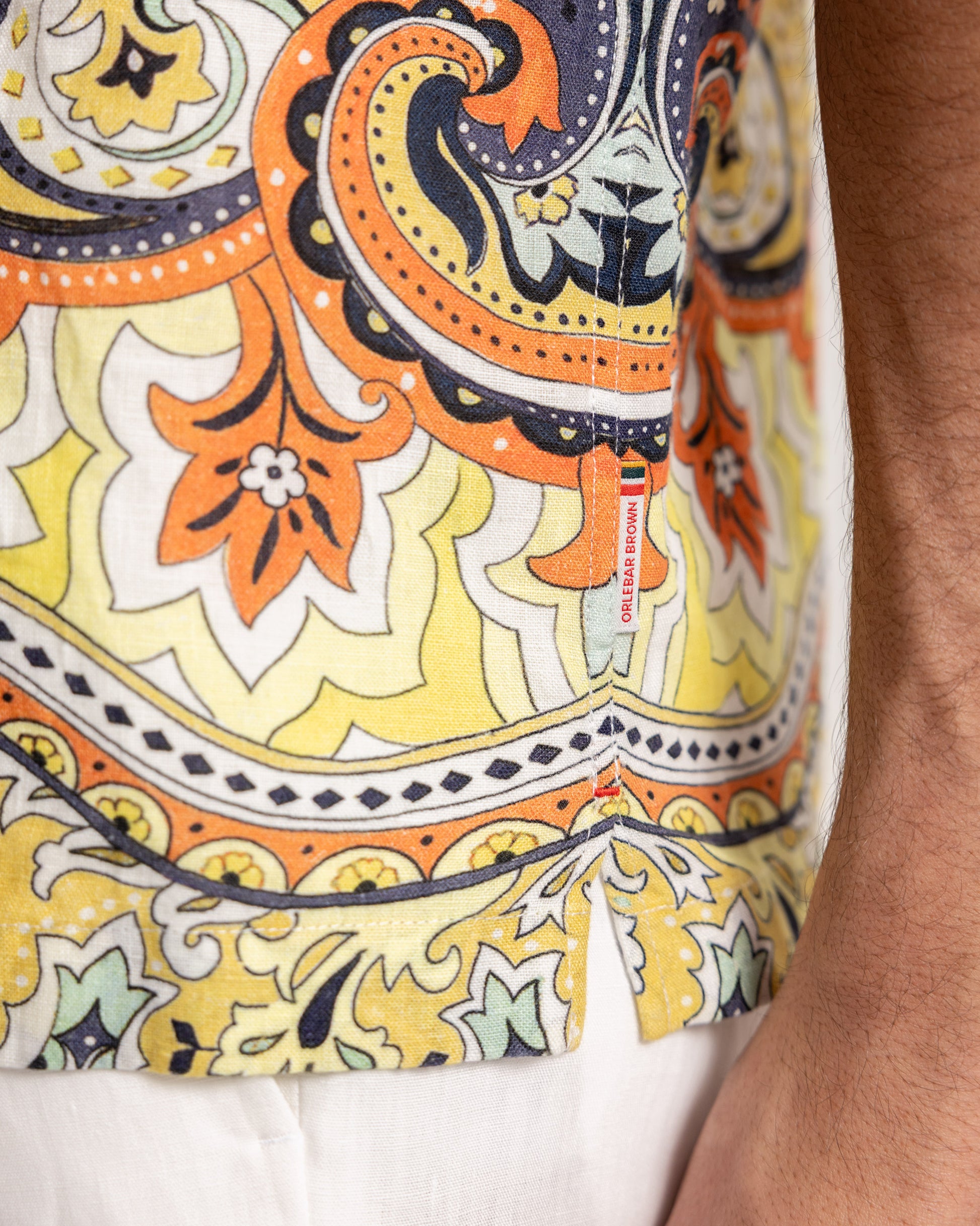 Closeup detailing of multicolour print shirt and white trousers