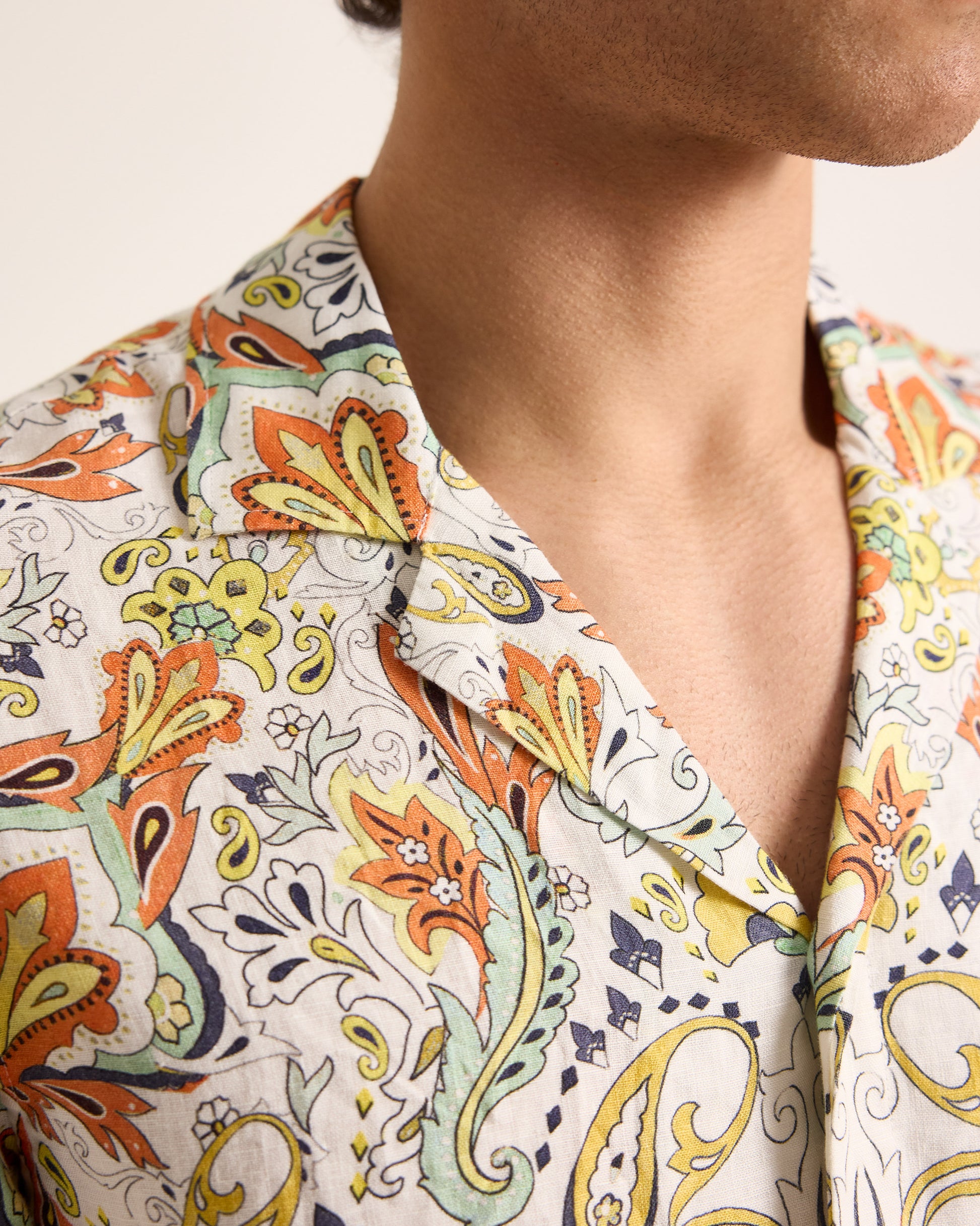 Close-up of a person wearing a colorful patterned shirt with a neutral background