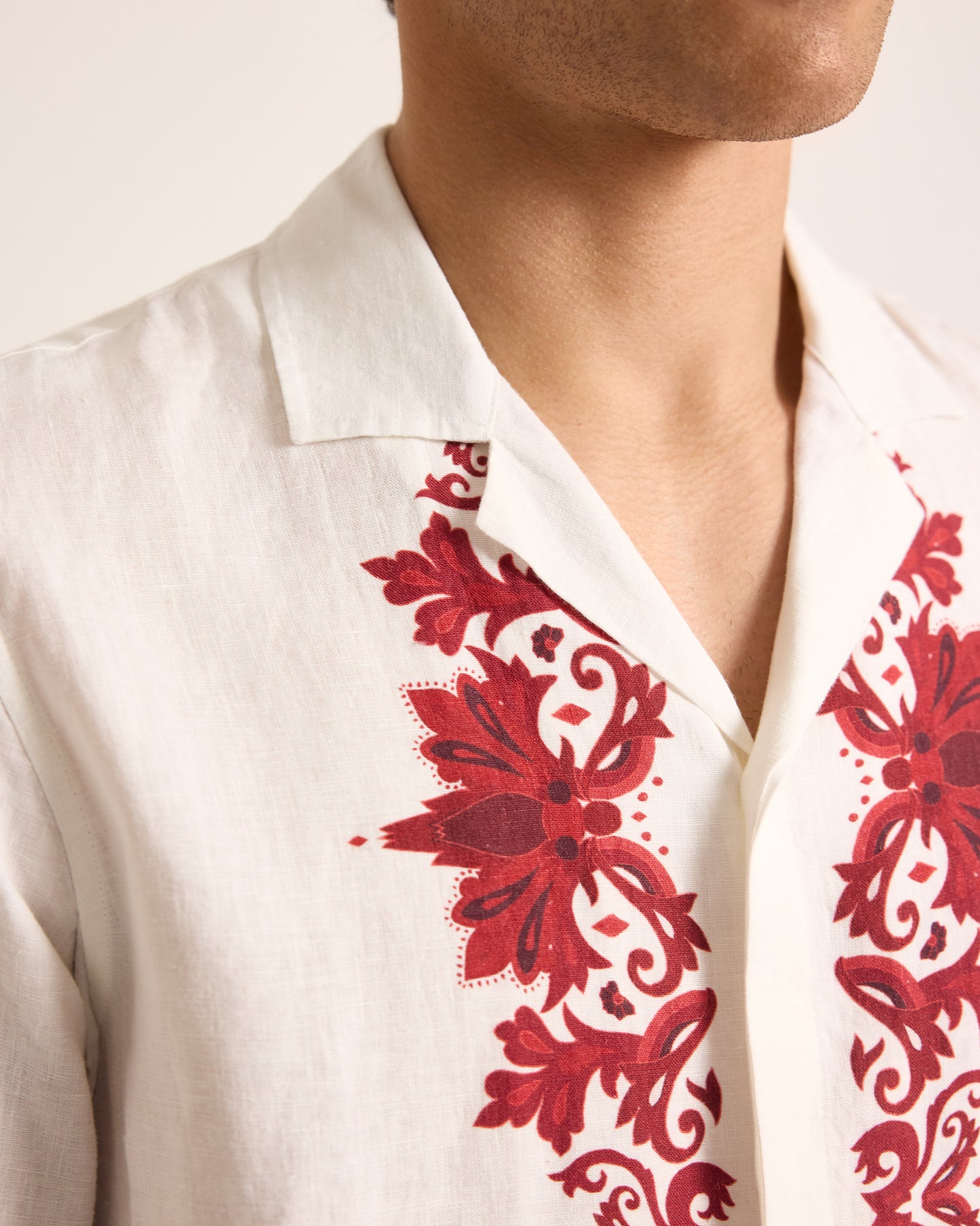 White shirt with red floral embroidery on a plain background