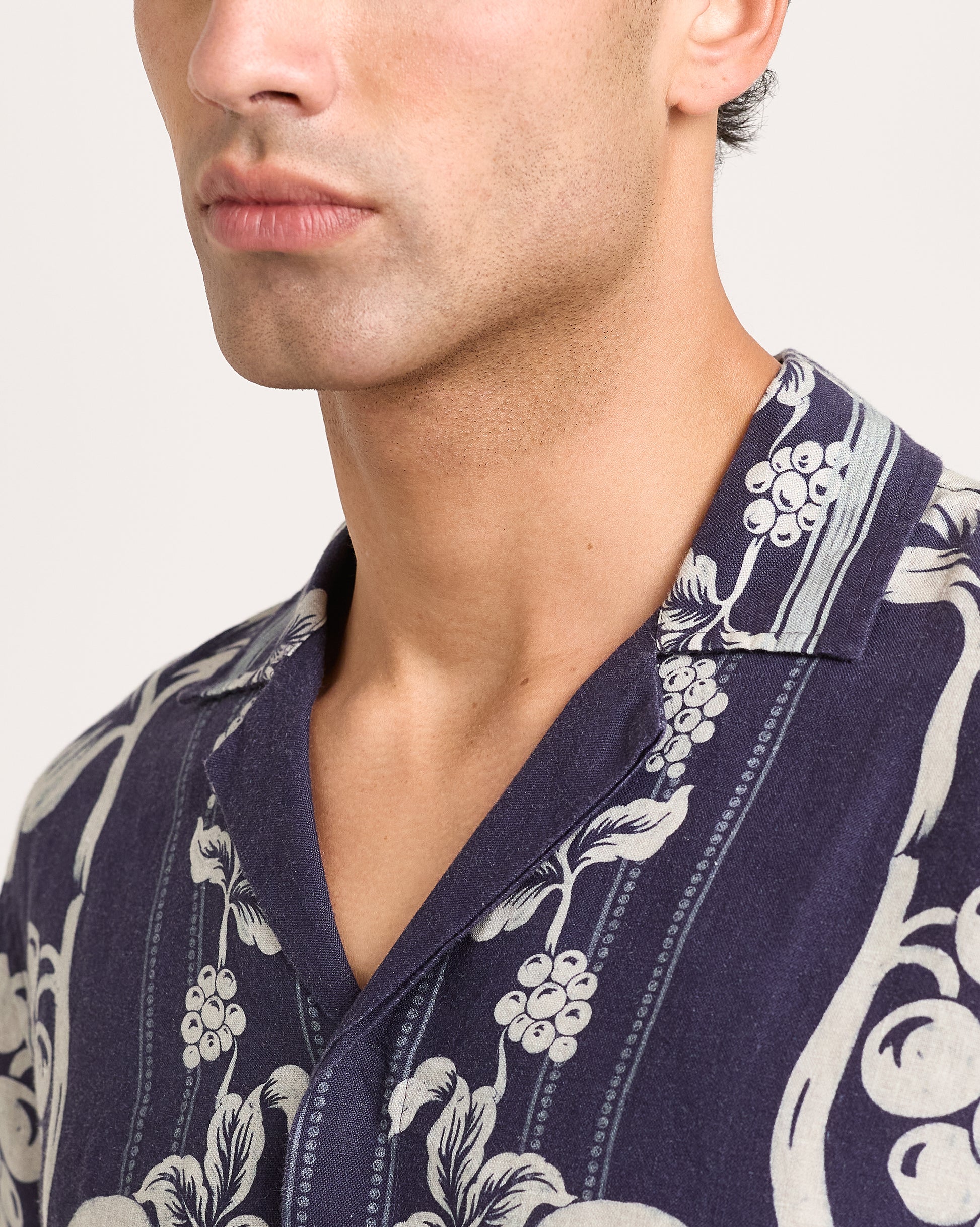 Man wearing a navy blue floral patterned shirt against a white background