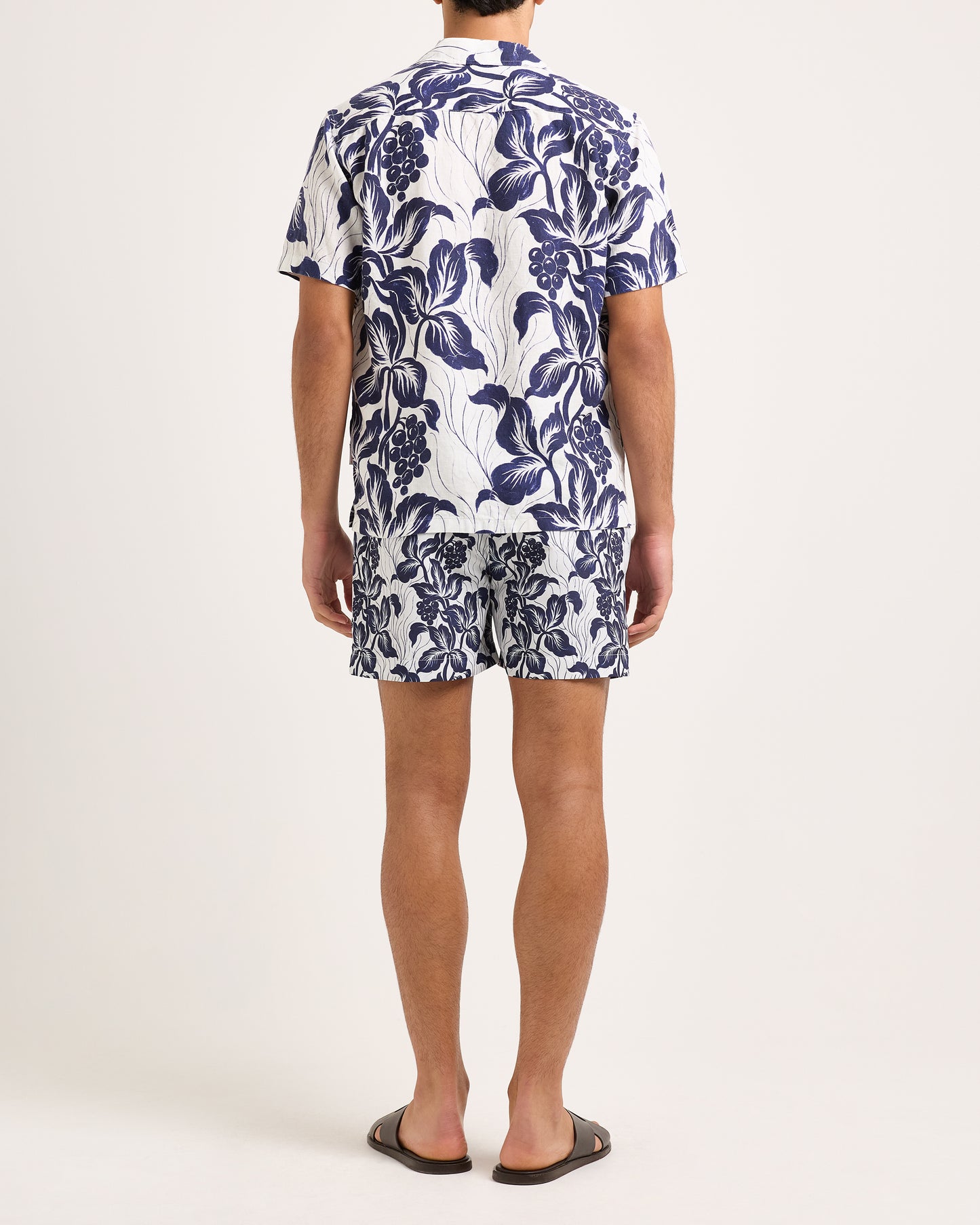 Person wearing a blue floral shirt and shorts on a white background