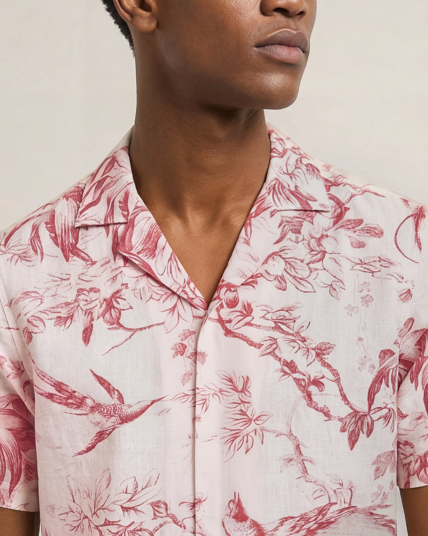 Person wearing a pink floral patterned shirt against a neutral background