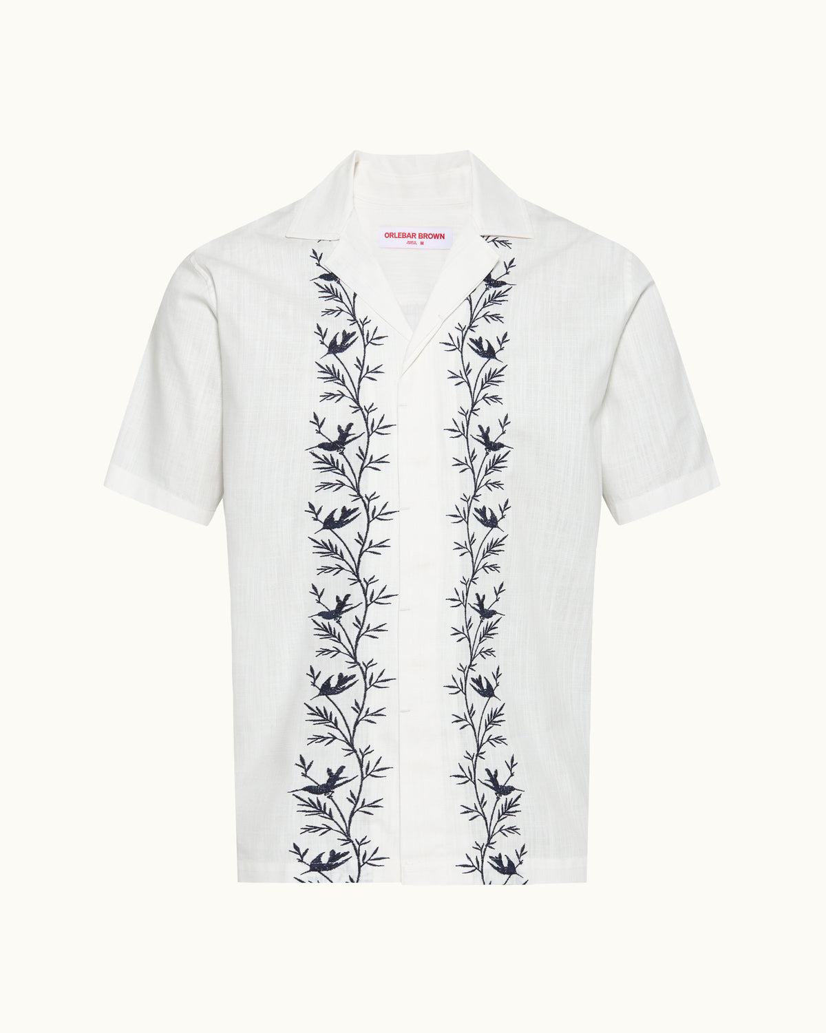 White linen shirt with navy embroidery detail on a plain background