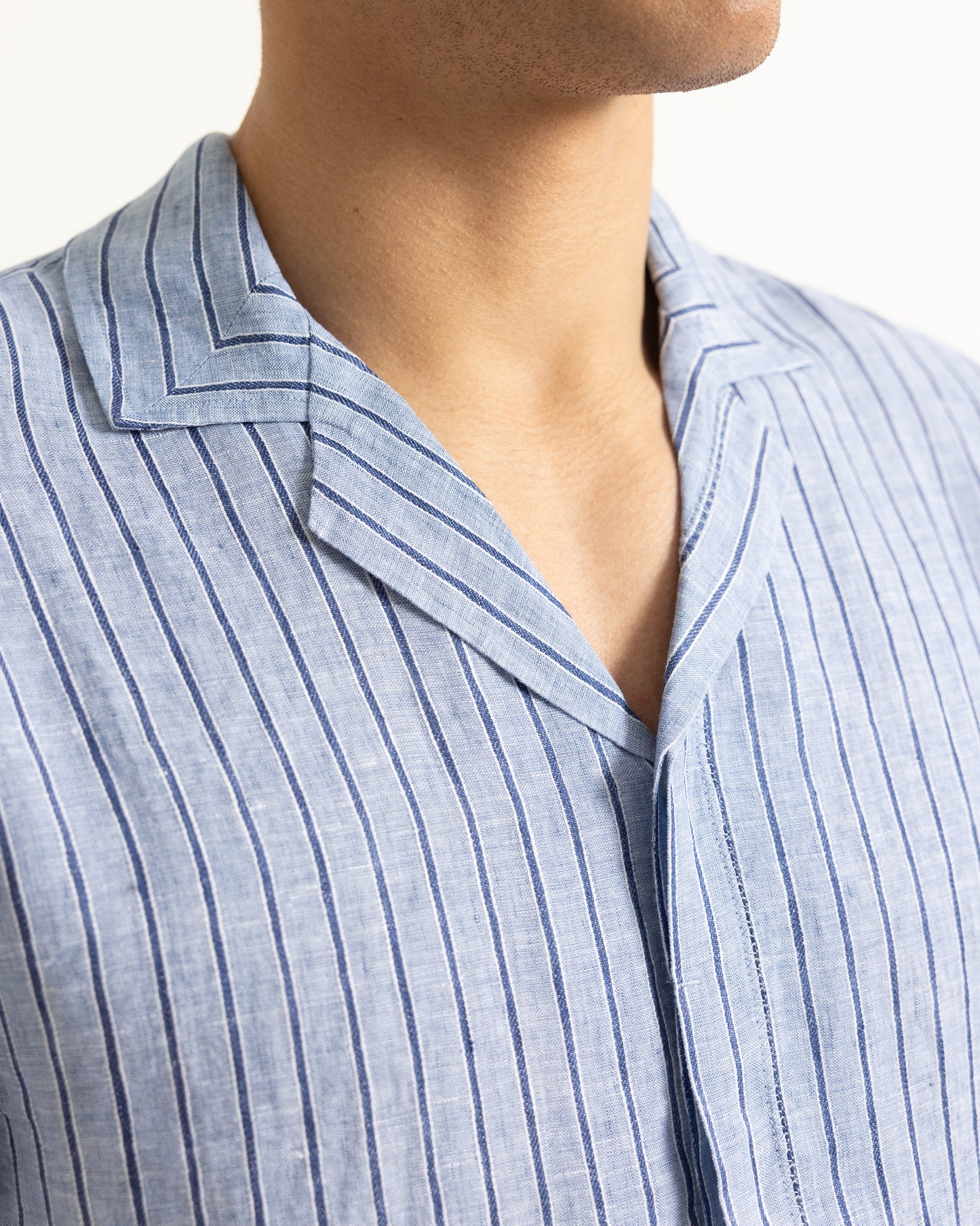 Close-up of a person wearing a light blue striped shirt with a collar.