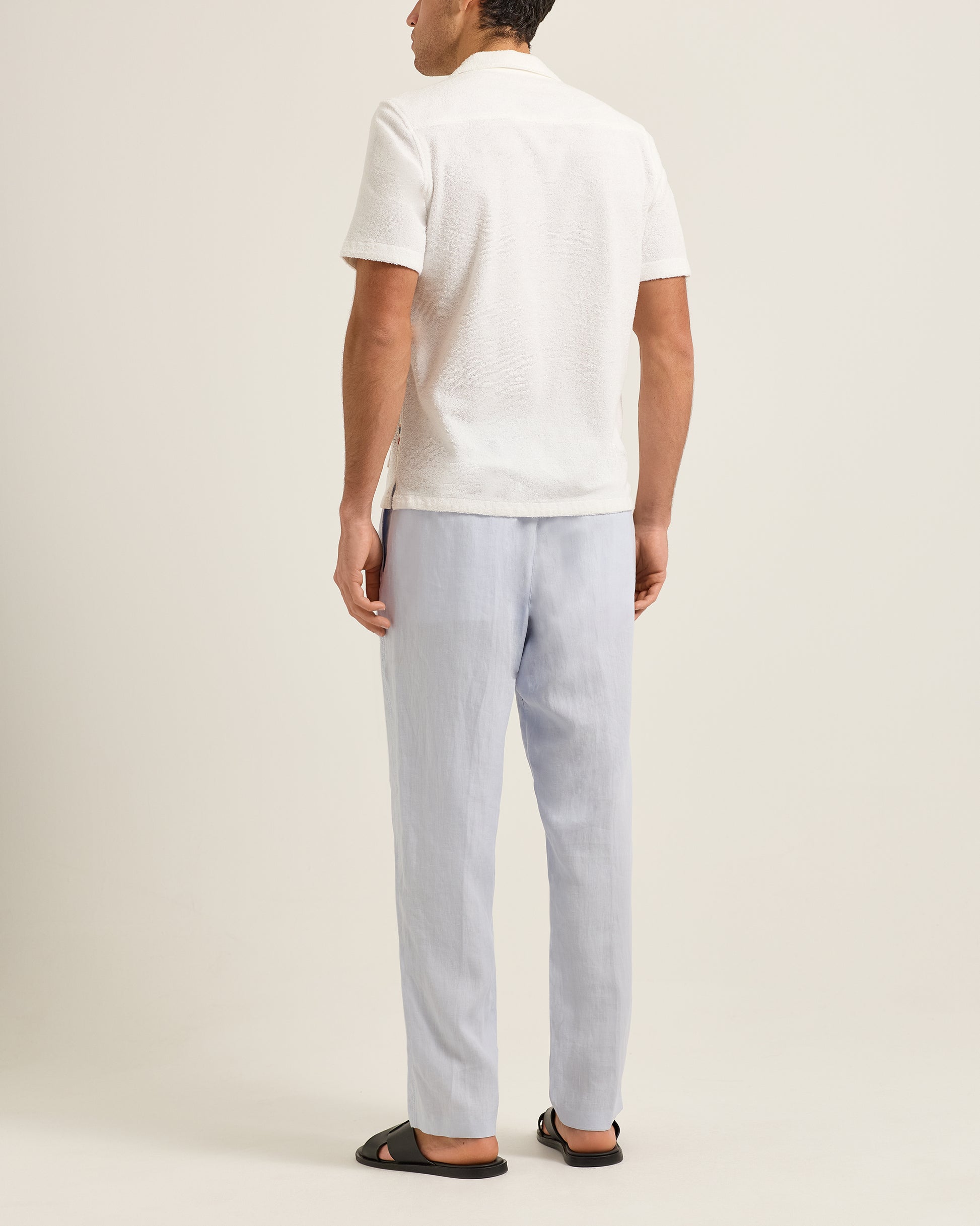 Person wearing a white polo shirt and light blue pants on a plain background