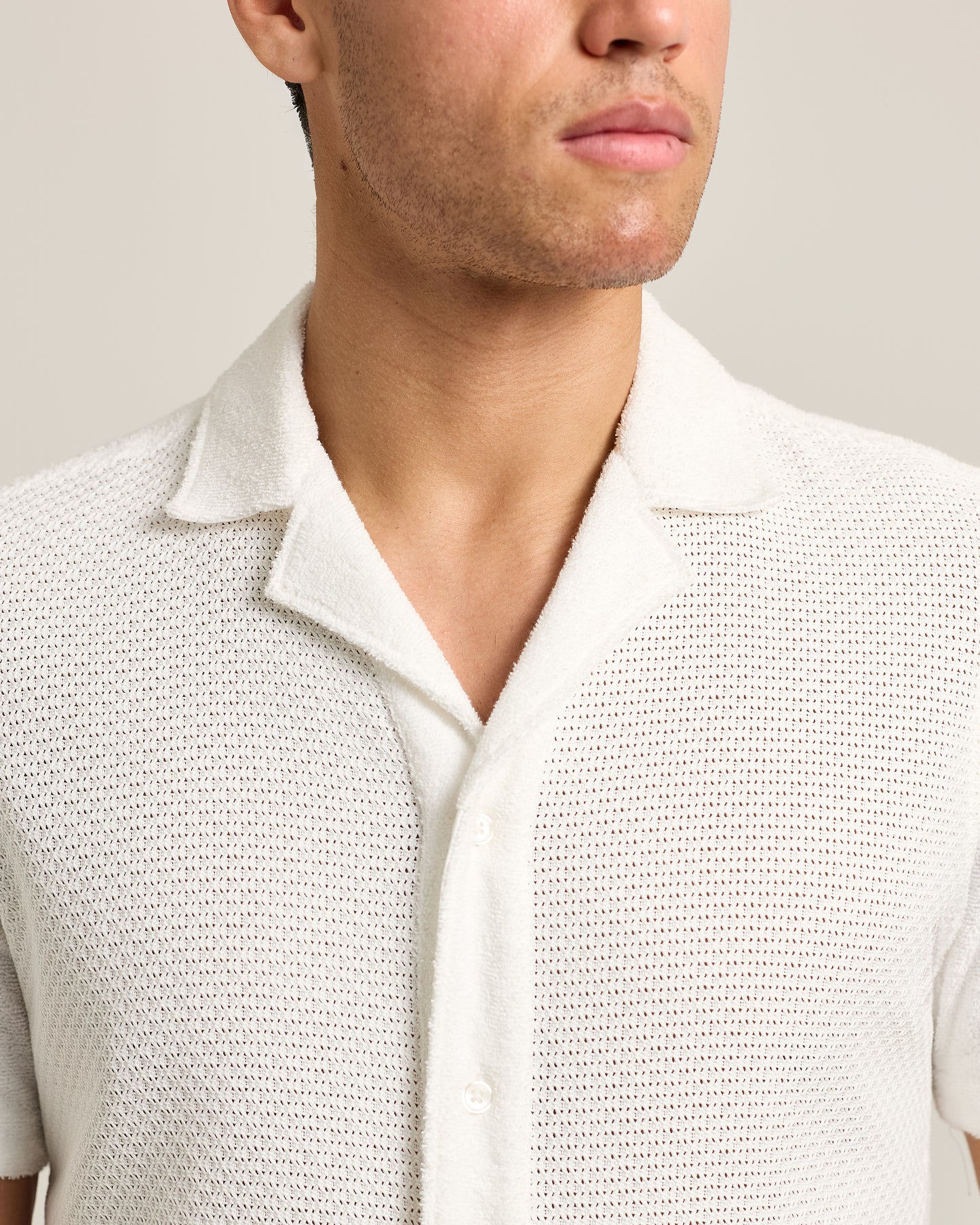 Close-up of a person wearing a textured light gray shirt against a neutral background