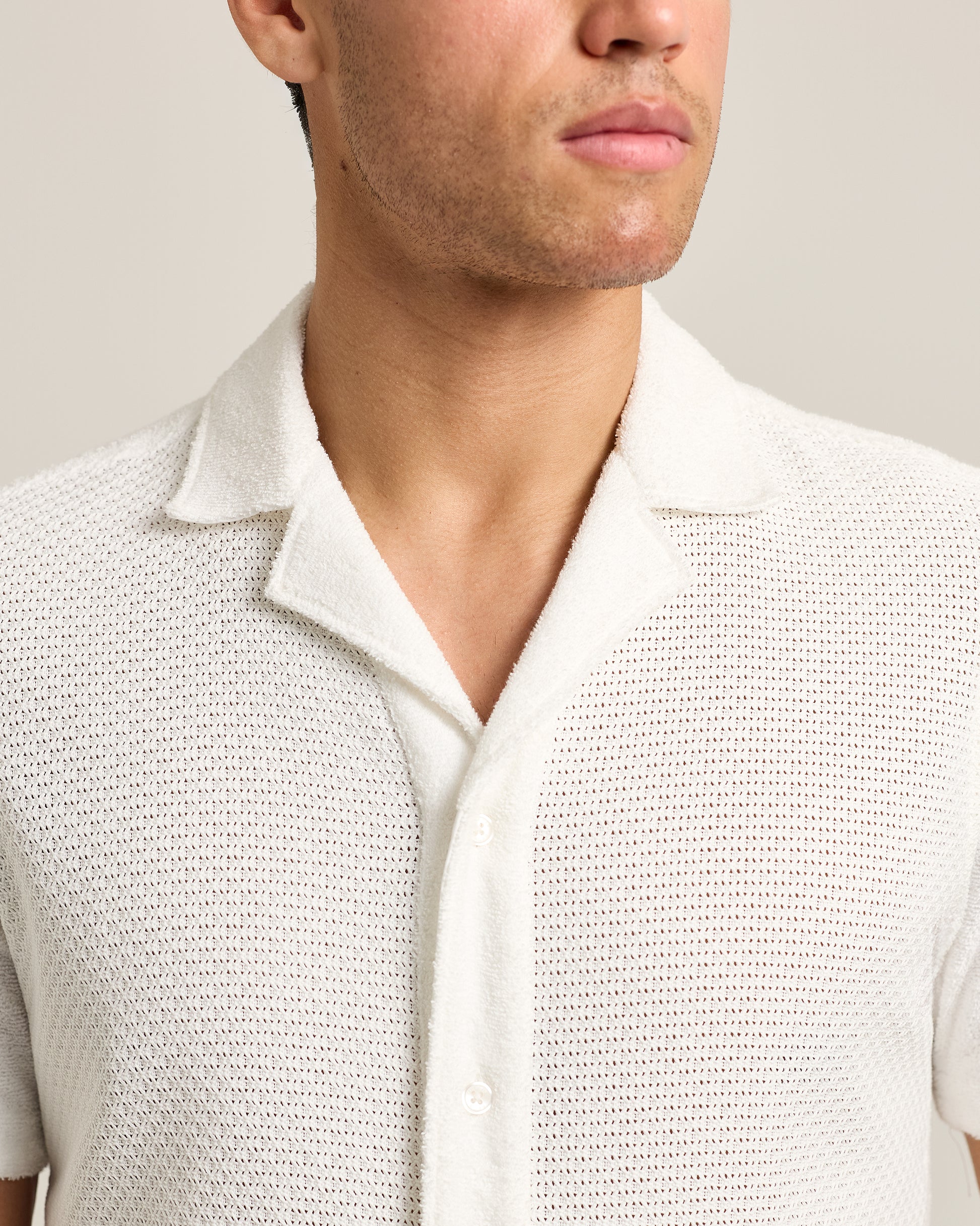 Close-up of a person wearing a textured light gray shirt against a neutral background