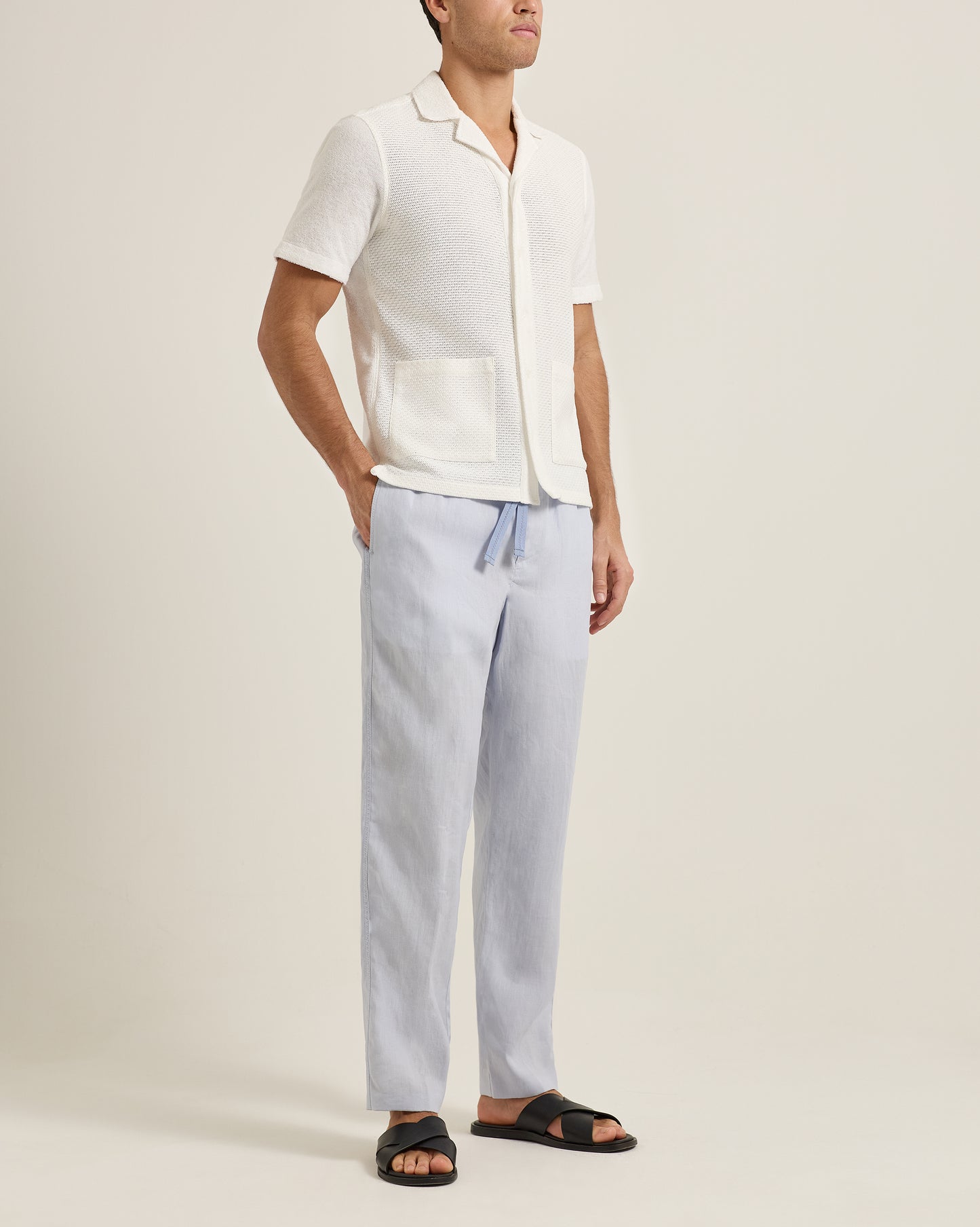 Person wearing a white shirt and light blue pants on a plain background