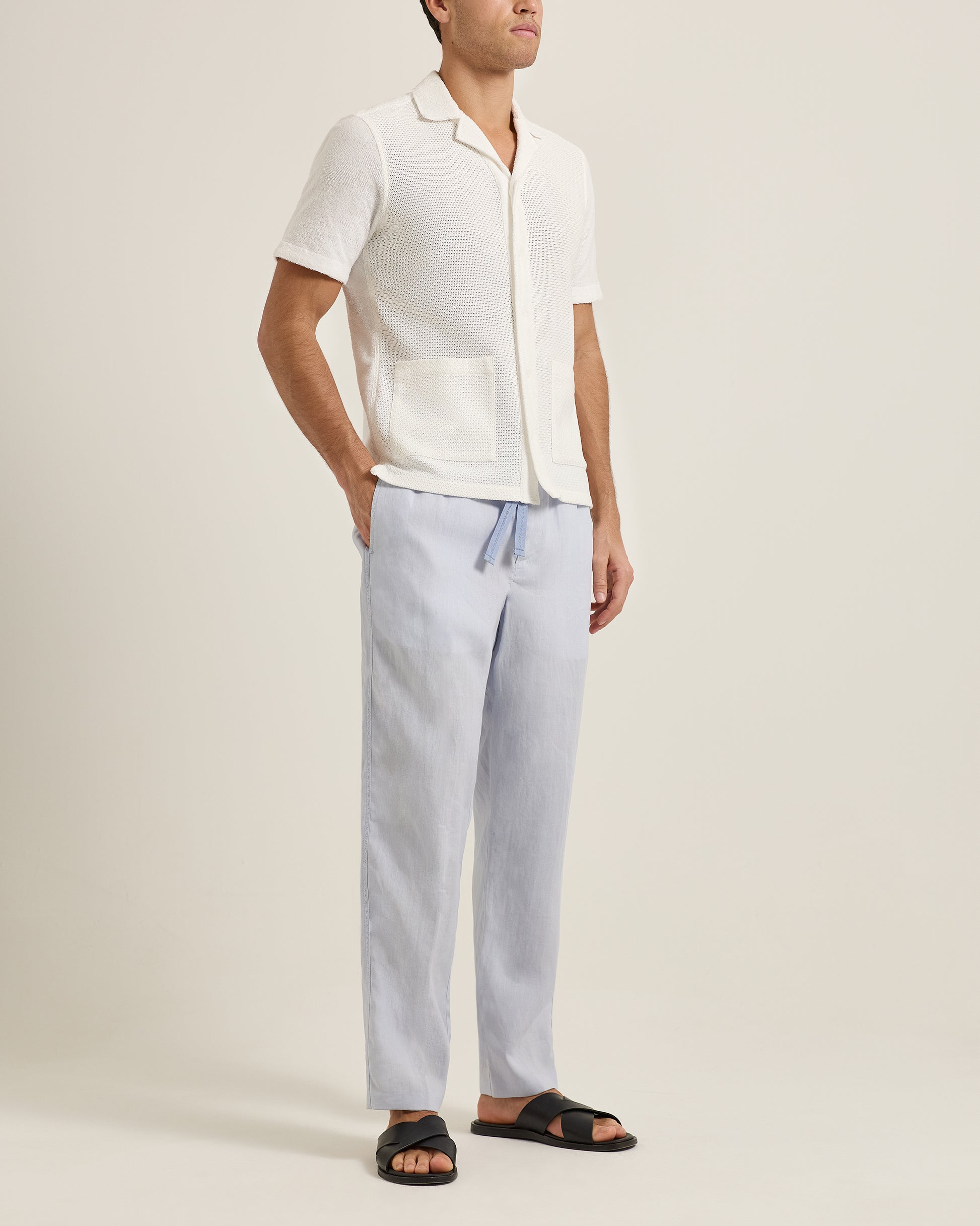 Person wearing a white shirt and light blue pants on a plain background