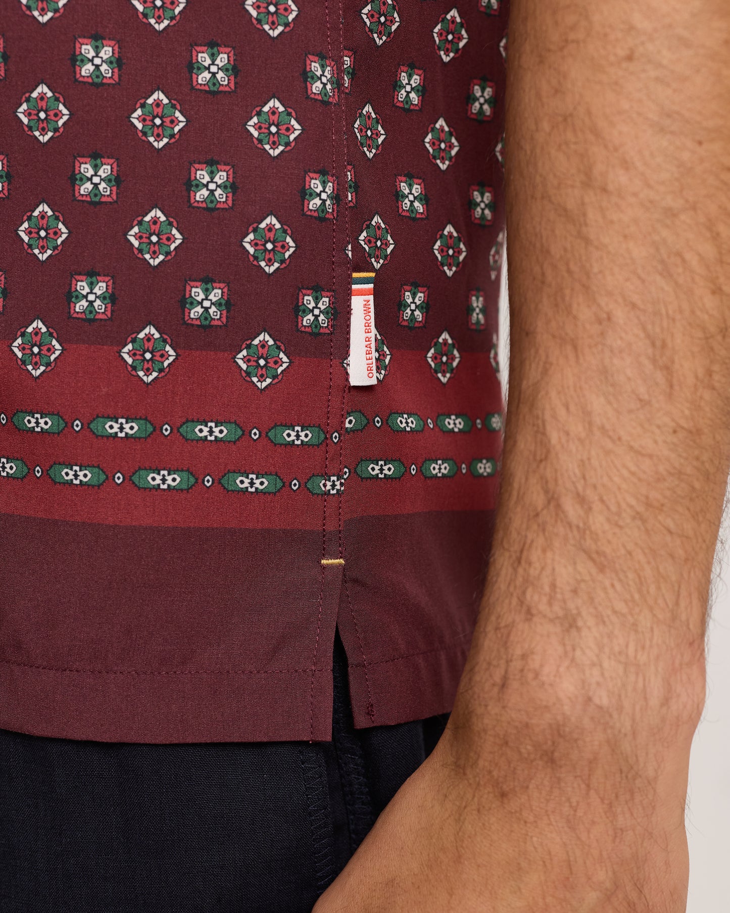 Close-up of maroon shirt with a geometric pattern on a plain background