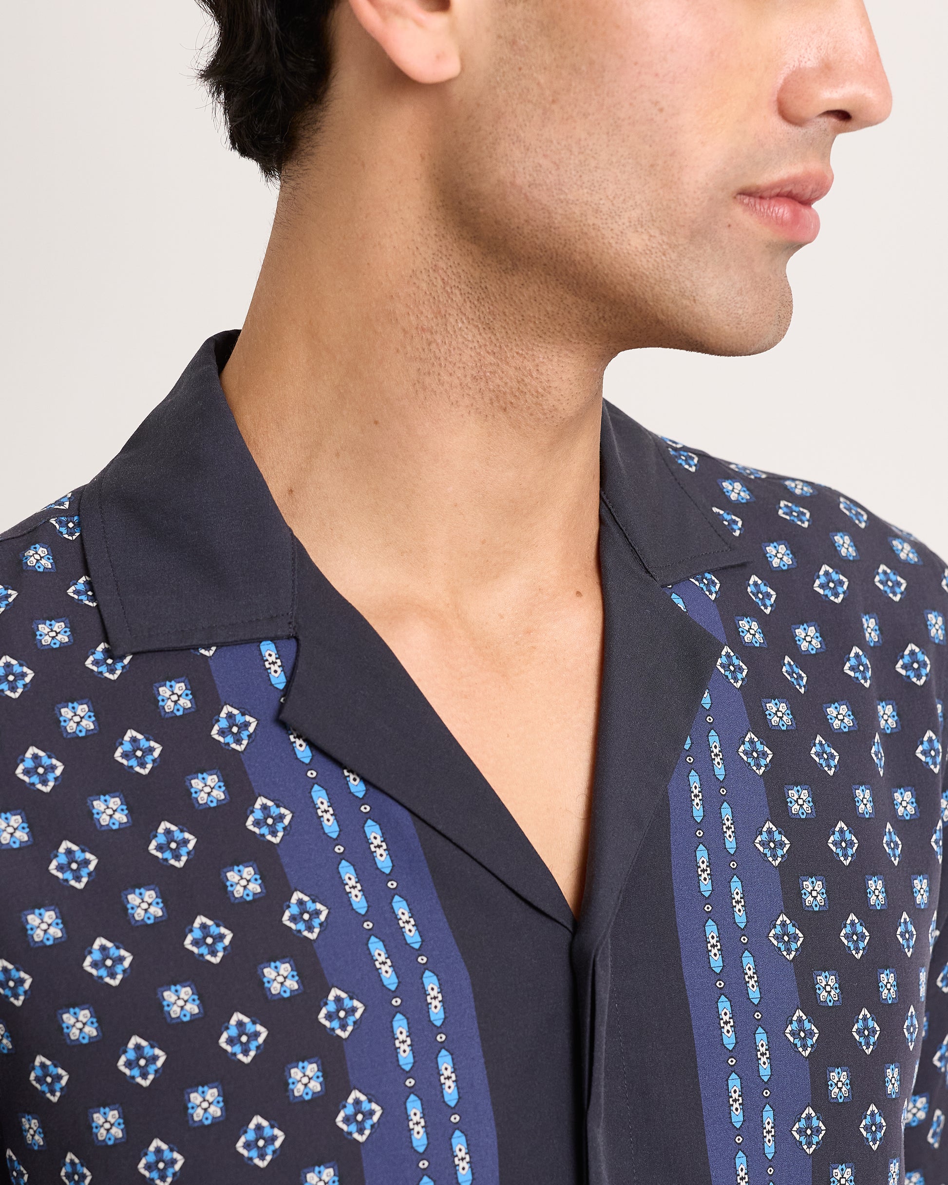 Close-up of model wearing a navy patterned shirt on a white background