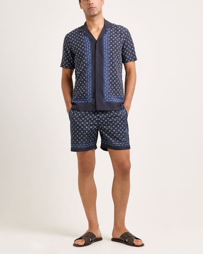 Man wearing a navy patterned shirt and shorts set on a white background