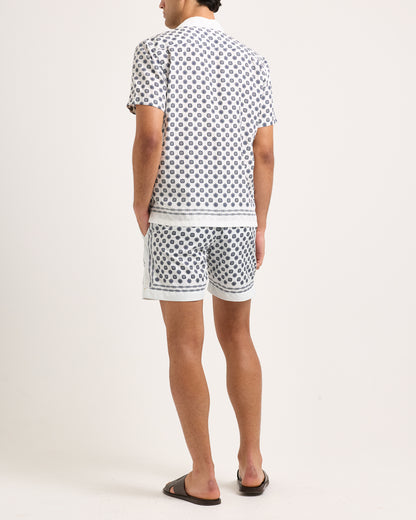 Model wearing short-sleeve shirt with a black geometric pattern and matching shorts on a white background