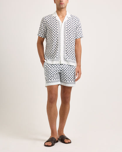 Model wearing short-sleeve shirt with a black geometric pattern and matching shorts on a white background