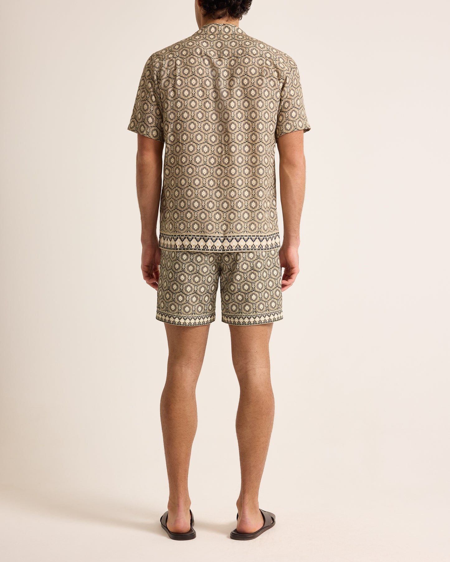 Person wearing a patterned shirt and shorts set on a plain background