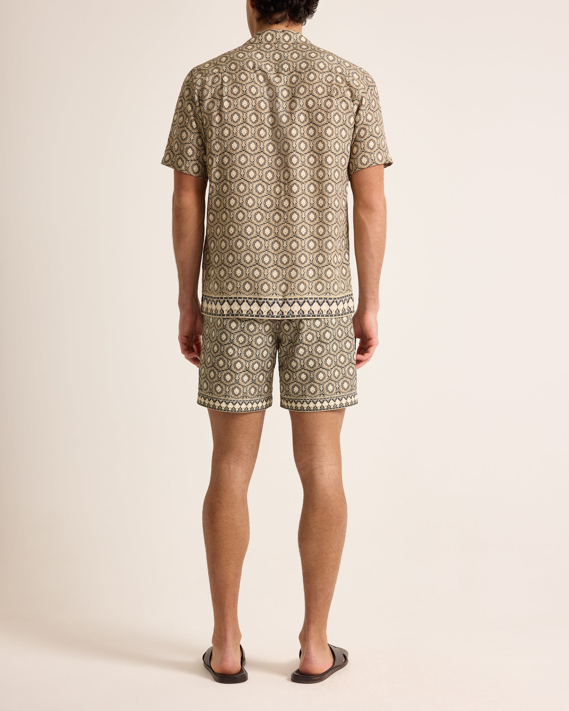 Person wearing a patterned shirt and shorts set on a plain background