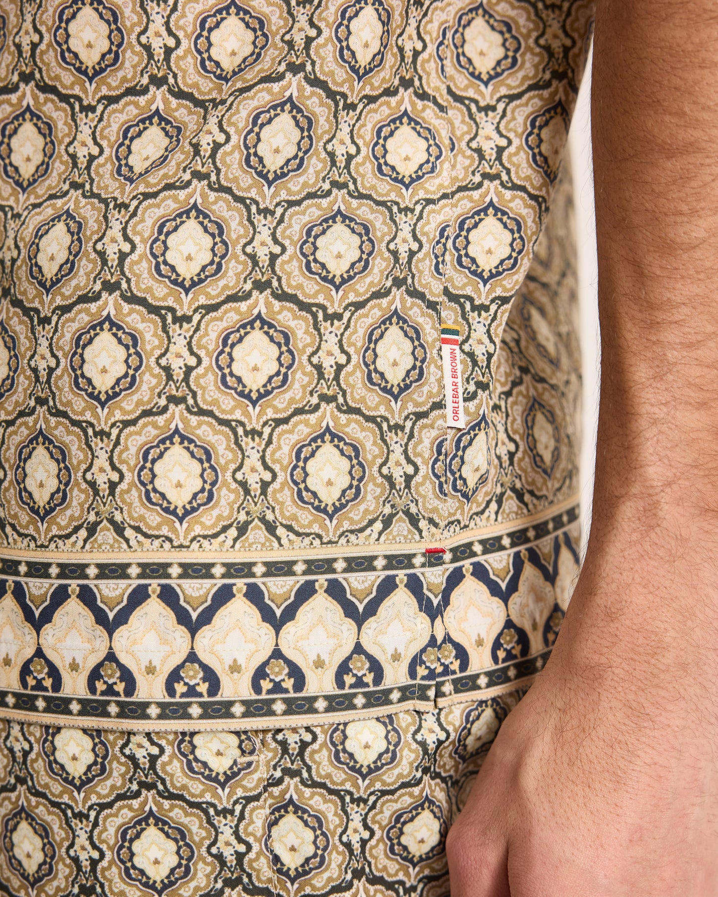 Patterned fabric with a visible brand label on a person's arm.
