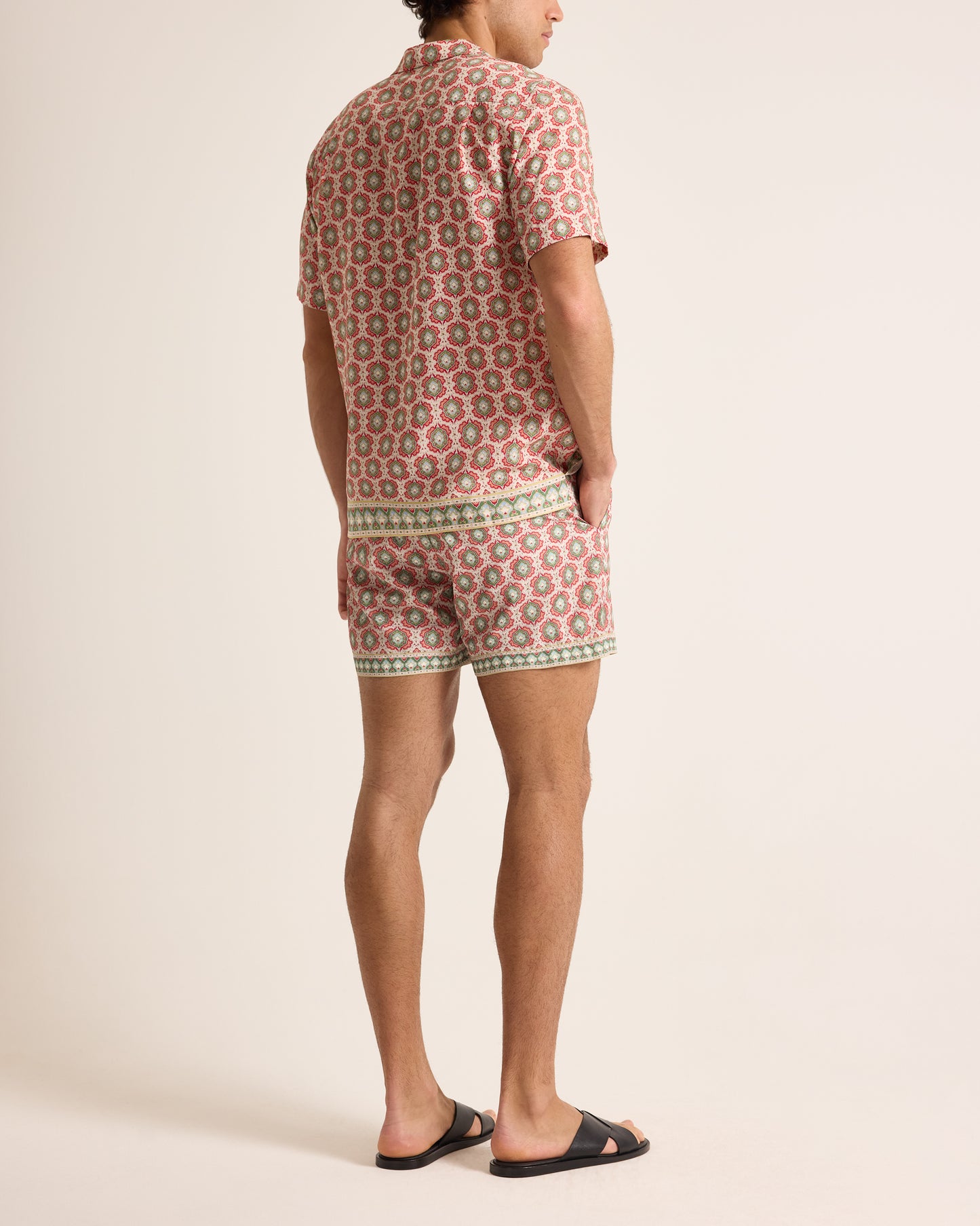 Person wearing a patterned shirt and shorts on a plain background