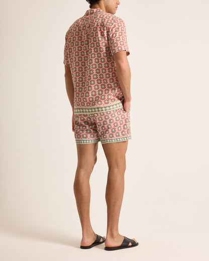 Person wearing a patterned shirt and shorts on a plain background