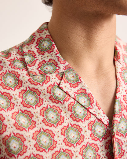 Close-up of a person wearing a patterned top with a neutral background