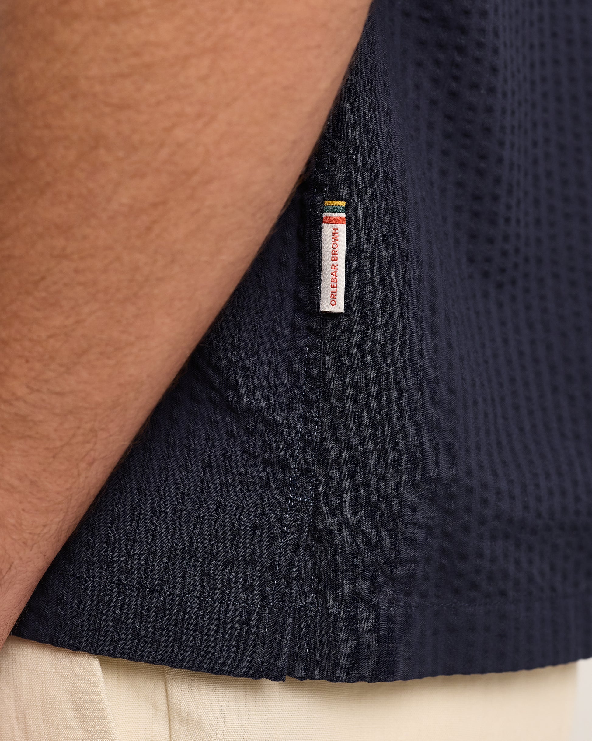 Navy blue textured shirt with a brand label on a neutral background